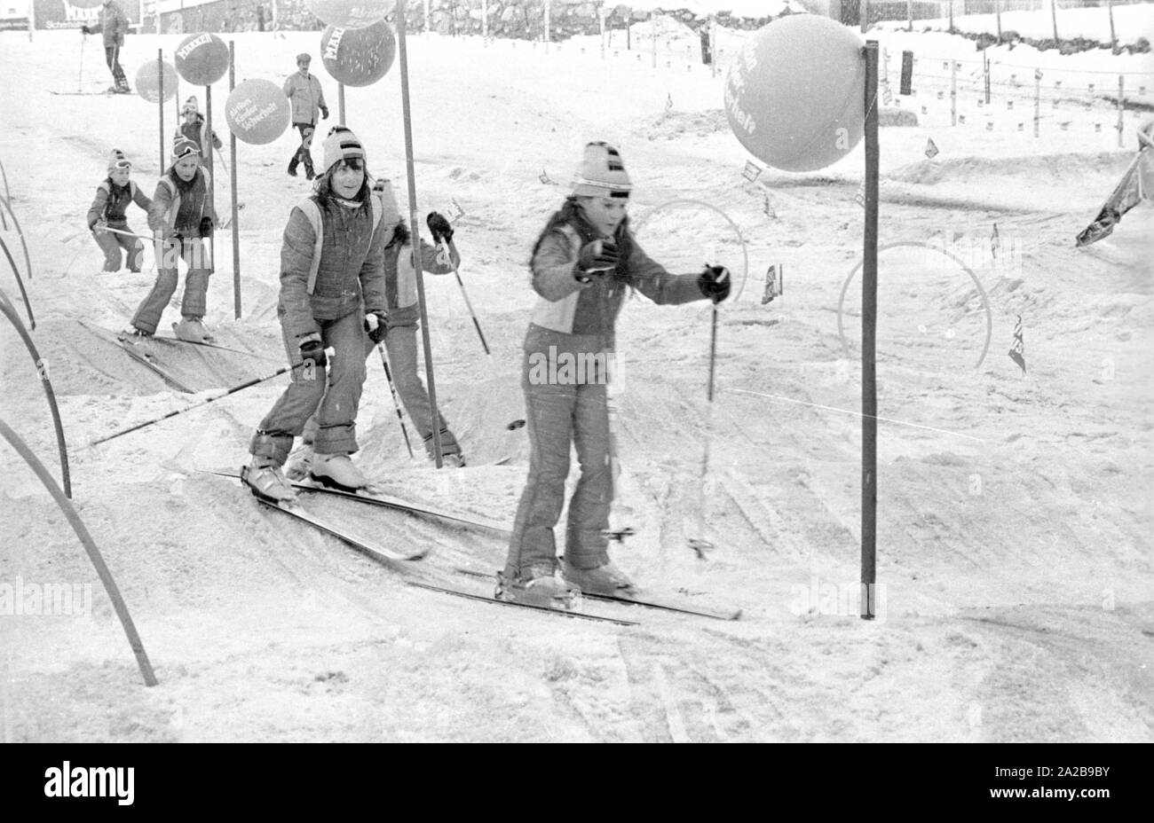 Kinder in den Skikurs in der Skischule Garmisch. Die Firma "Marker" wirbt für seine Sicherheit Skibindungen mit Banner. Stockfoto