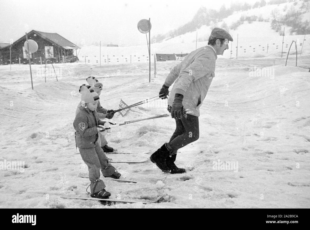 Kinder in den Skikurs in der Skischule Garmisch. Die Firma "Marker" wirbt für seine Sicherheit Skibindungen mit Banner. Stockfoto