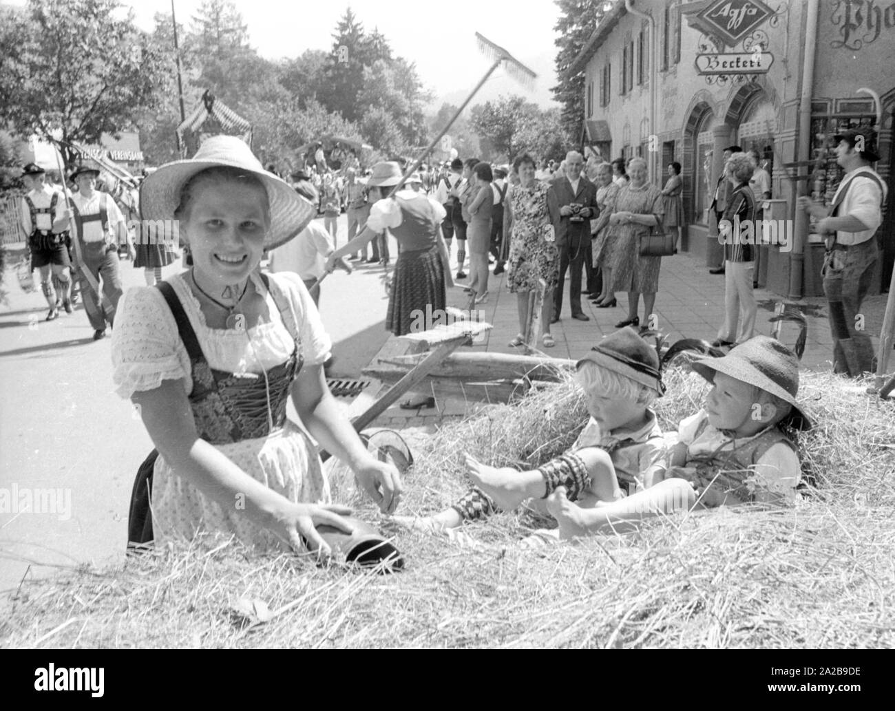 Menschen in traditionellen Kostümen mit landwirtschaftlichen Geräten an einem Trachtenumzug in Oberbayern. Stockfoto