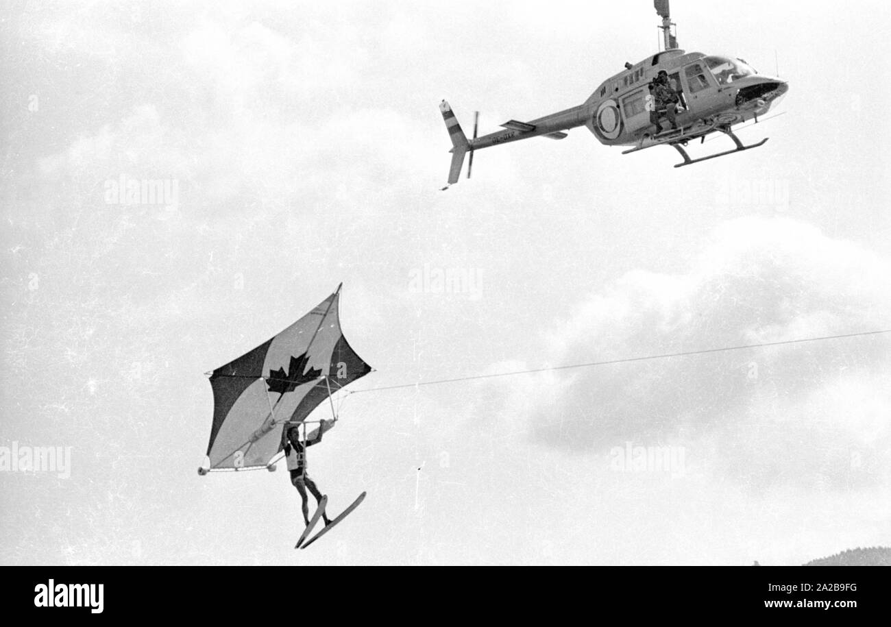 Die deutschen Schlager Sänger Udo Jürgens beim Drachenfliegen auf einem See. Er wird von einem Kamerateam in einem Hubschrauber gefilmt. Stockfoto