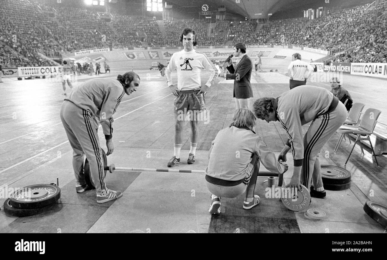 Fußballspieler Franz Beckenbauer plantscht im Gewichtheben am Sportpressefest in der Münchner Olympiahalle. Hinter Ihm, der Athlet und Moderator Erhard Keller. Stockfoto