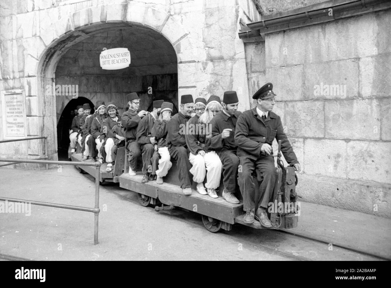 Die Besucher des Tourist mine alzbergwerk Berchtesgaden Start ihrer Tour mit einer Fahrt mit der Grubenbahn. Sie sind in Bergmannskluft (einheitliche's Miner) gekleidet. Stockfoto