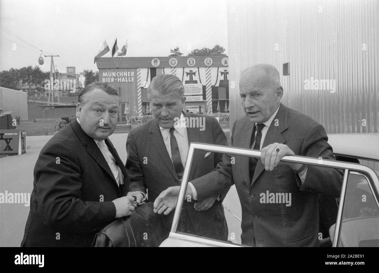 Ingenieur Wernher von Braun (Mitte) besucht den internationalen Transport Ausstellung (IVA) auf der Theresienhöhe in München. Die Seilbahn im Hintergrund ist auch Teil des IVA. Stockfoto