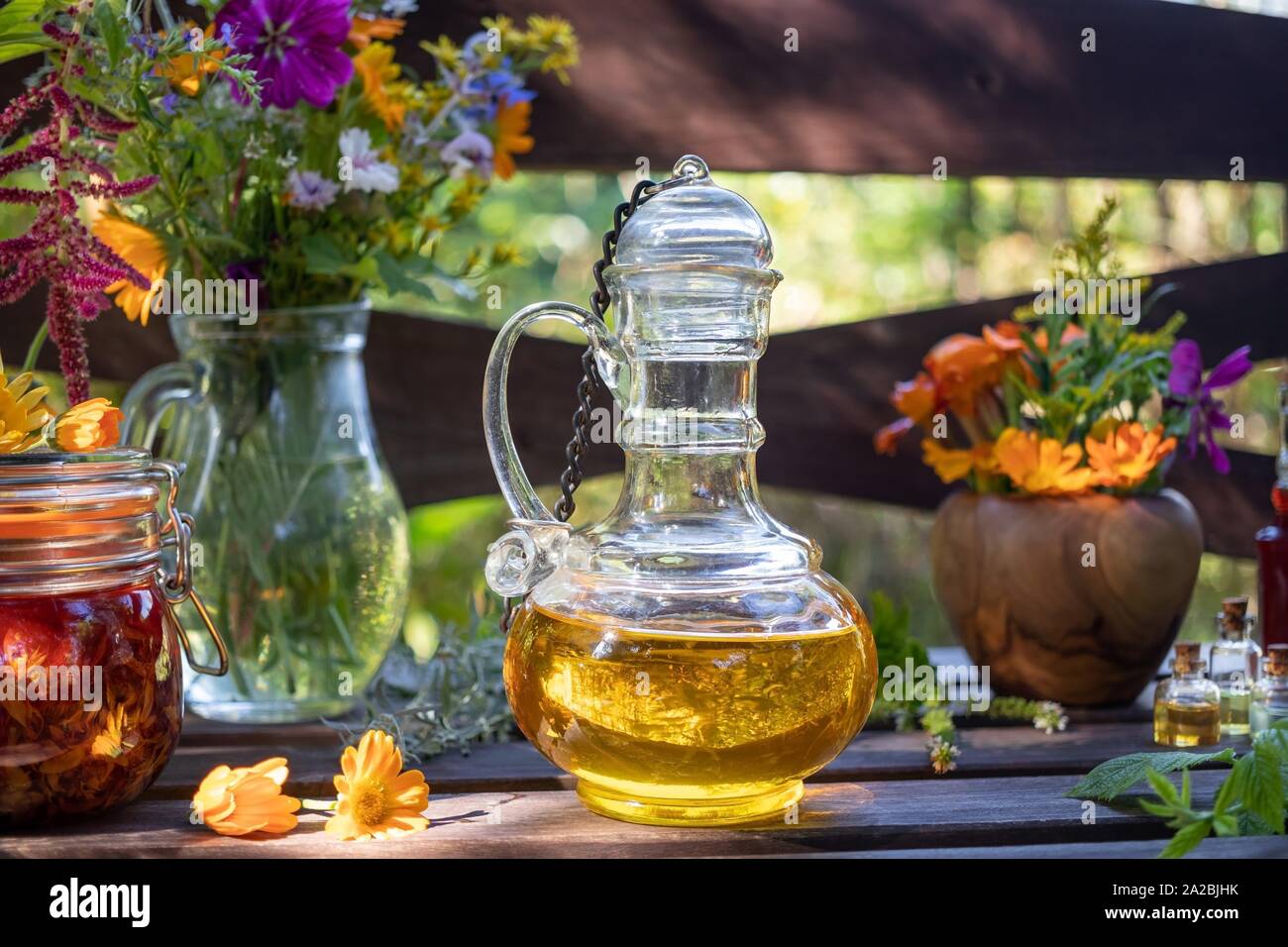 Flaschen Kräuter und ätherische Öle, die mit frischen Pflanzen und Blumen  im Hintergrund Stockfotografie - Alamy