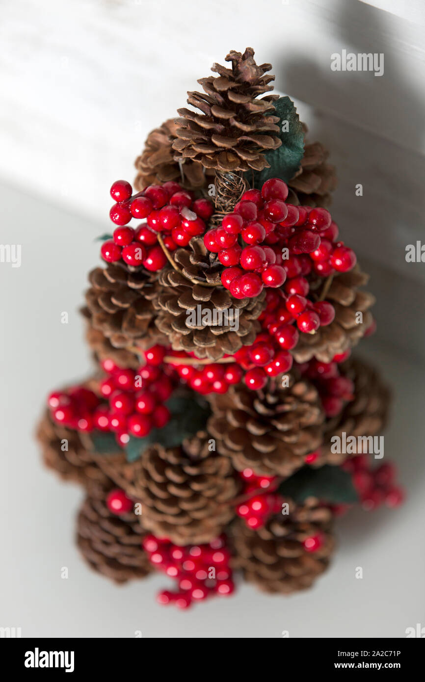 Zarte Tannenzapfen Weihnachtsbaum mit roten Holly Beeren Dekoration Stockfoto