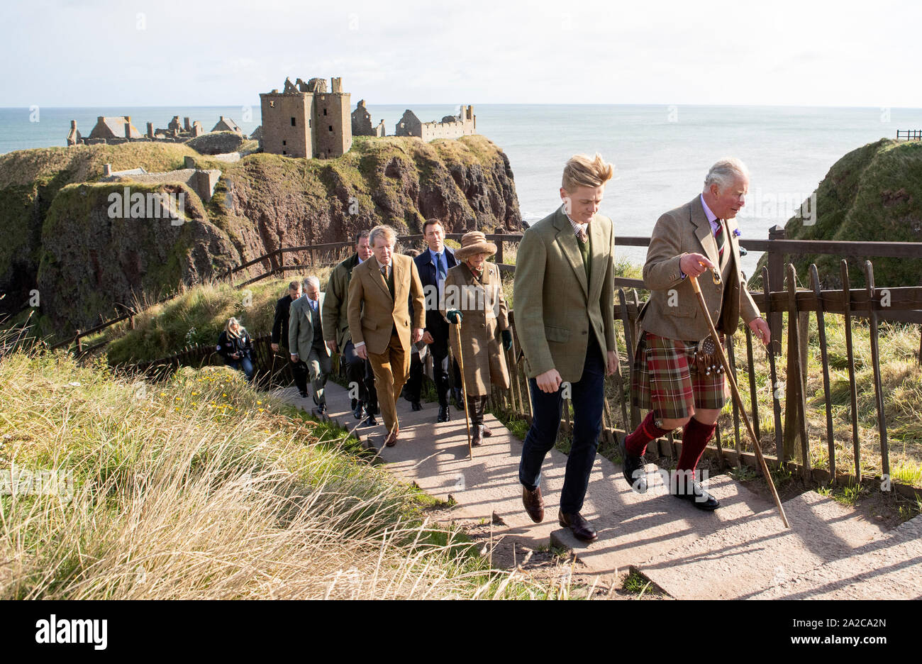 Der Prinz von Wales, bekannt als The Duke of Rothesay, während in Schottland, wird durch Schloss Inhaber George Pearson (vorne links) bei einem Besuch in Dunnottar Castle, das auf einer Klippe Festung, die einst die Heimat war der Grafen Marischal, in der Nähe von Stonehaven begleitet. Stockfoto