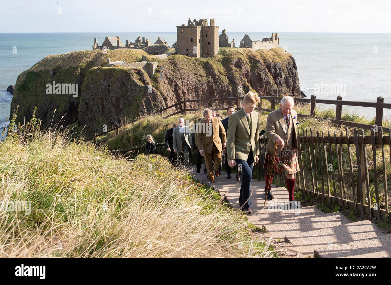 Der Prinz von Wales, bekannt als The Duke of Rothesay, während in Schottland, wird durch Schloss Inhaber George Pearson (vorne links) bei einem Besuch in Dunnottar Castle, das auf einer Klippe Festung, die einst die Heimat war der Grafen Marischal, in der Nähe von Stonehaven begleitet. Stockfoto