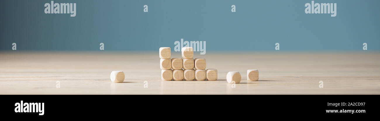 In der breiten Ansicht Bild eines unfertigen Struktur der Holz- Würfel mit einigen von ihnen liegen auf einem Schreibtisch verstreut. Über blauen Hintergrund. Stockfoto