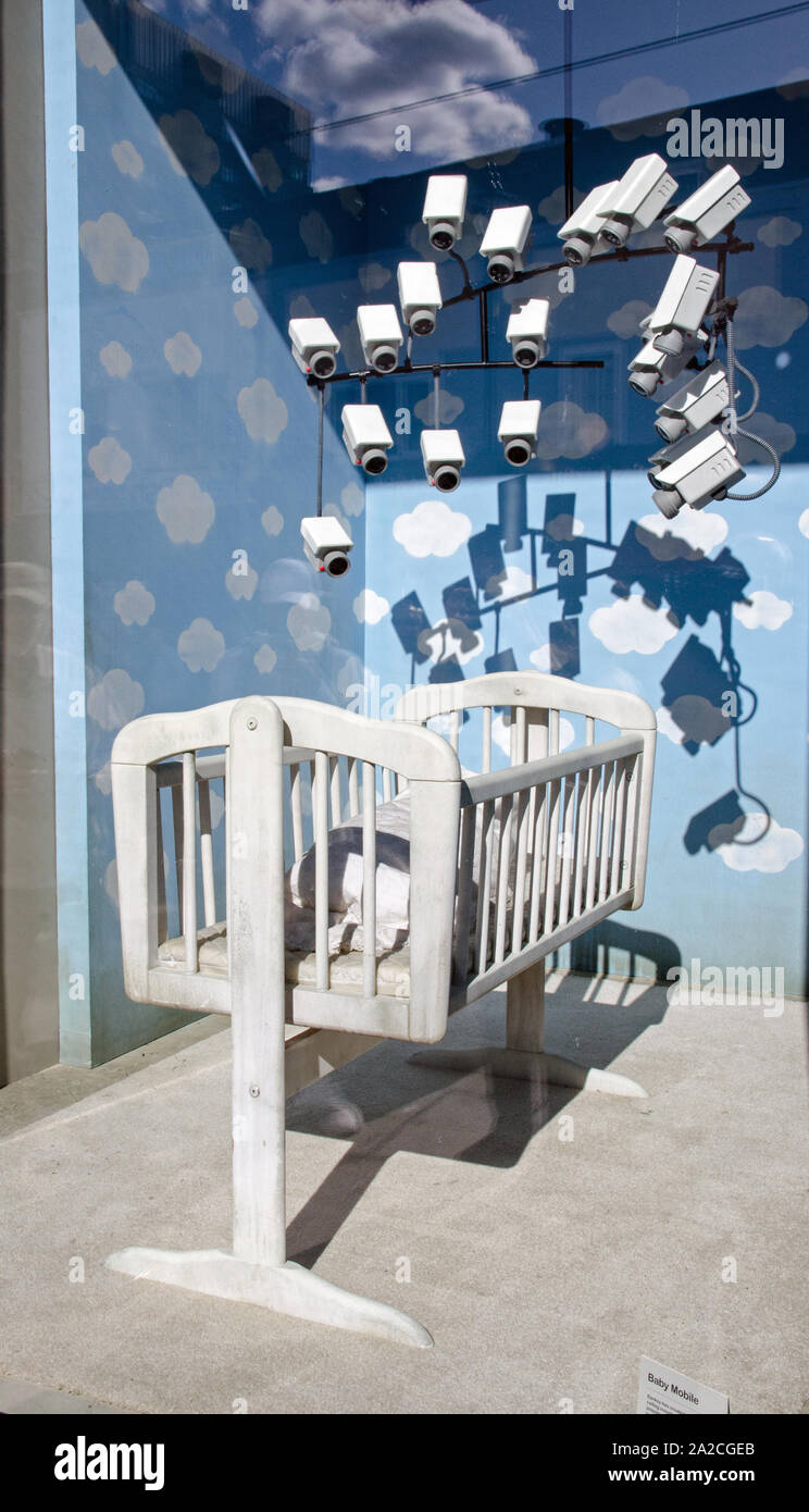 Banksy Baby Mobile auf Anzeige in ein Schaufenster in Croydon, London. Teil einer öffentlichen Kunst zeigen. Die mobile der CCTV-Kameras ist für ein Baby vorzubereiten Stockfoto