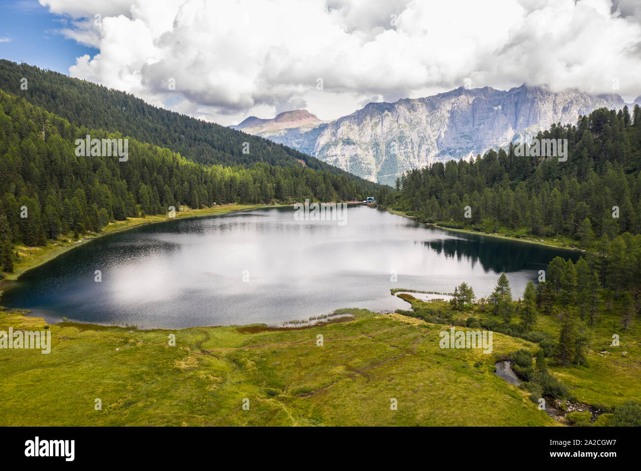 Foto mit Drohne über einem Bergsee in den Wäldern mit Unterstand und die Alpen im Hintergrund eingetaucht werden Stockfoto