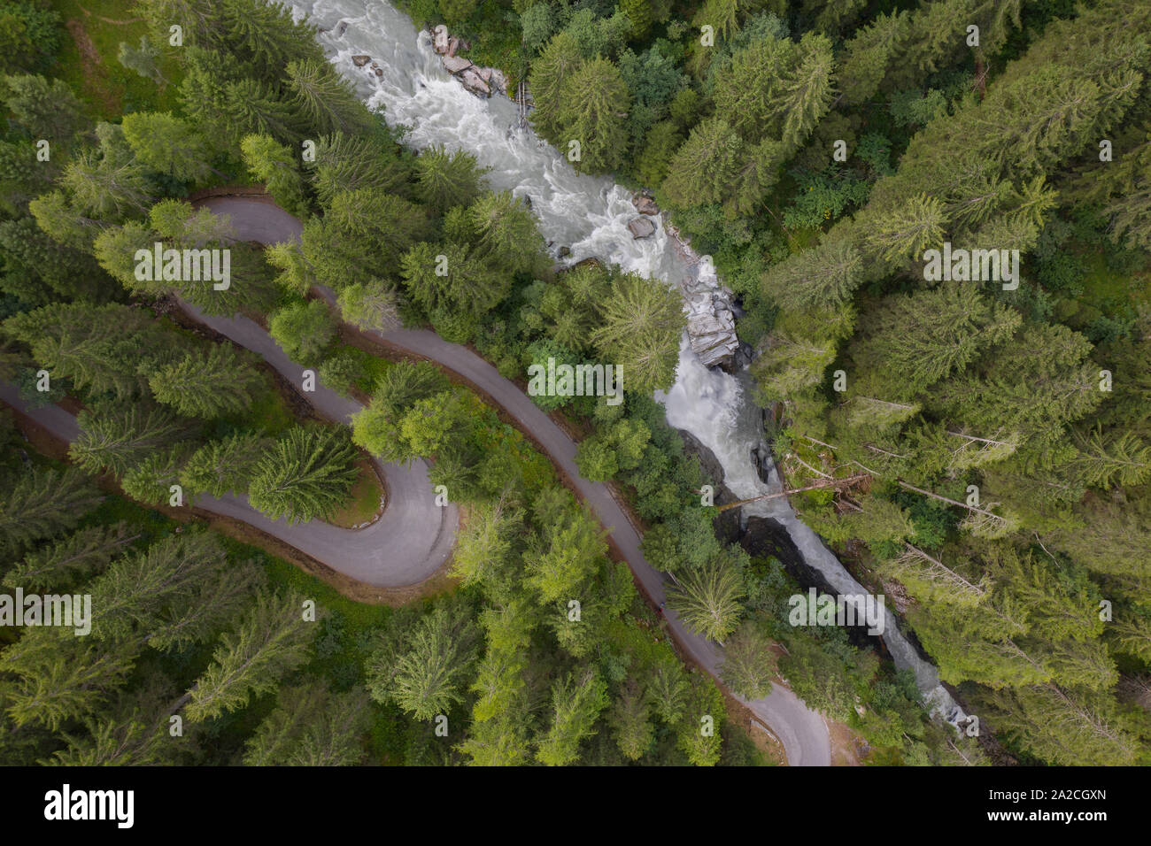 Foto mit einer Drohne über eine S-förmige Straße in einem Nadelbaum fliegen und einen Wasserfall in einem weichen Atmosphäre genommen Stockfoto