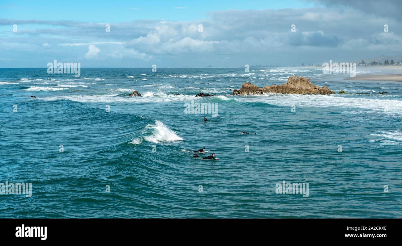 Surfer im Wasser an der Küste in der Nähe von Mount Manganui, Tauranga, Bay of Plenty, North Island, Neuseeland Stockfoto