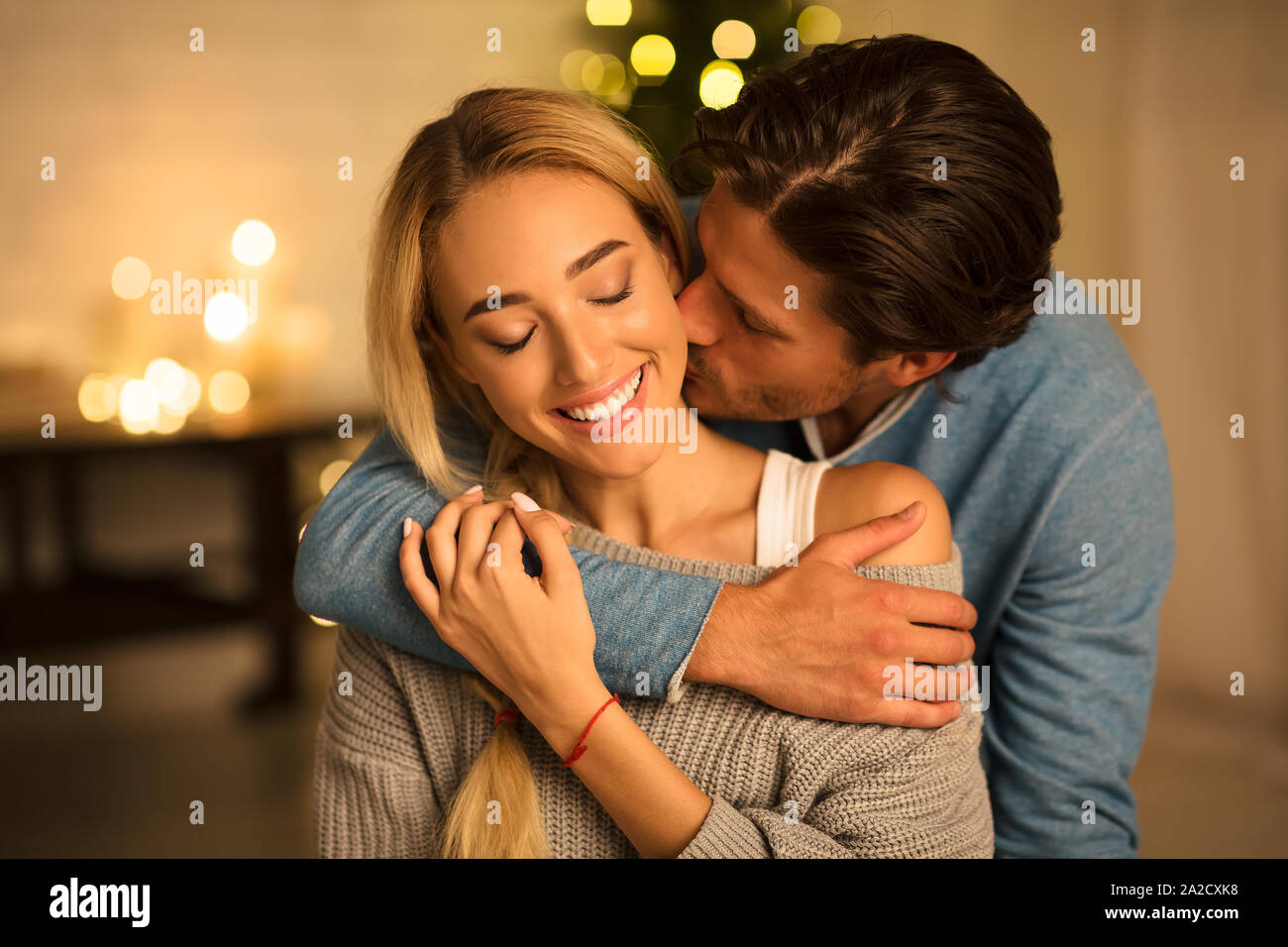 Bewegender Moment. Mann küssen Frau vor Weihnachtsbaum Stockfoto