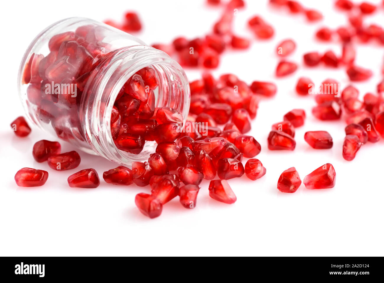 Granatapfel Samen in Glas Glas mit verstreuten Samen auf weißem Hintergrund Stockfoto