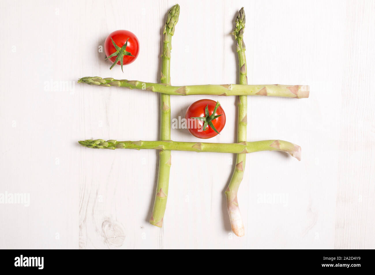 frischen rohen Spargel angelegt wie Nullen und Kreuze Spiel mit Tomaten Stockfoto