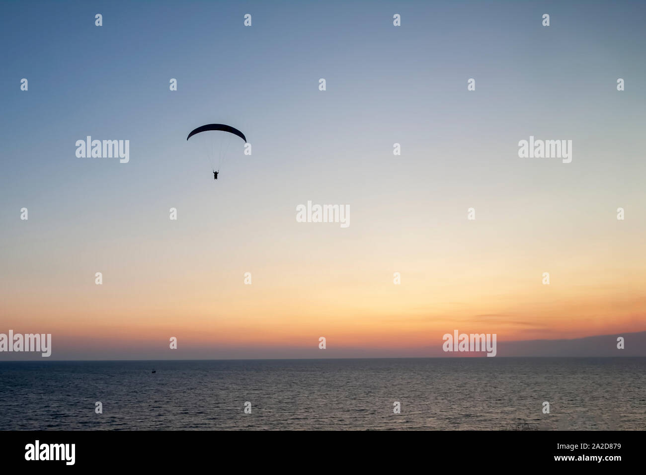 Gleitschirm mit einem Mann hoch in den blauen Himmel gegen die untergehende Sonne. Stockfoto