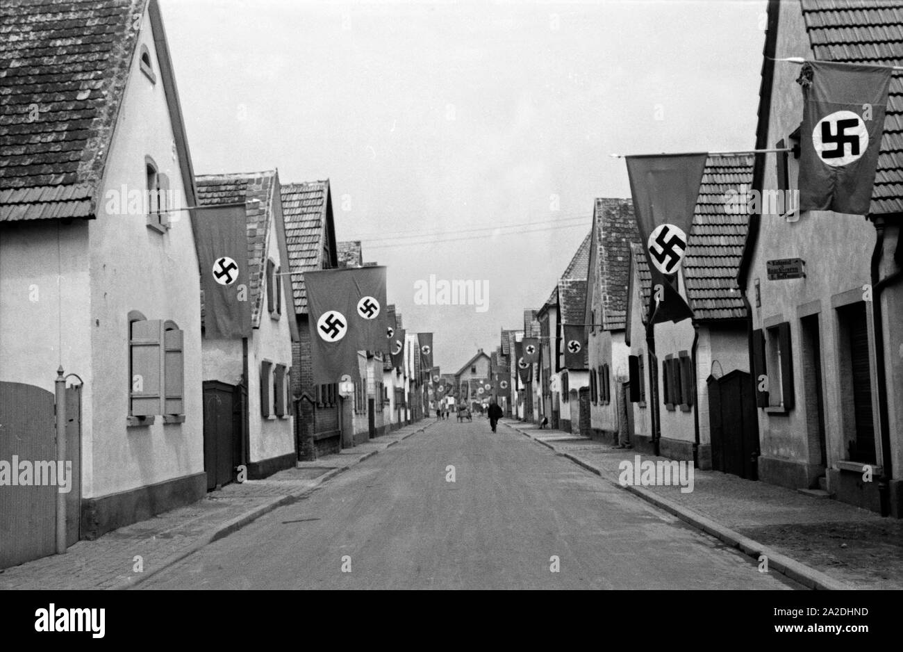 Zum Rettichfest sterben haben Feuerstelle von Schifferstadt ihre Häuser mit Hakenkreuzfahnen geschmückt, Deutschland 1930er Jahre. Die Bewohner von schifferstadt eingerichtet ihre Häuser mit Hakenkreuzfahnen zu den jährlichen Rettich fair, Deutschland 1930. Stockfoto