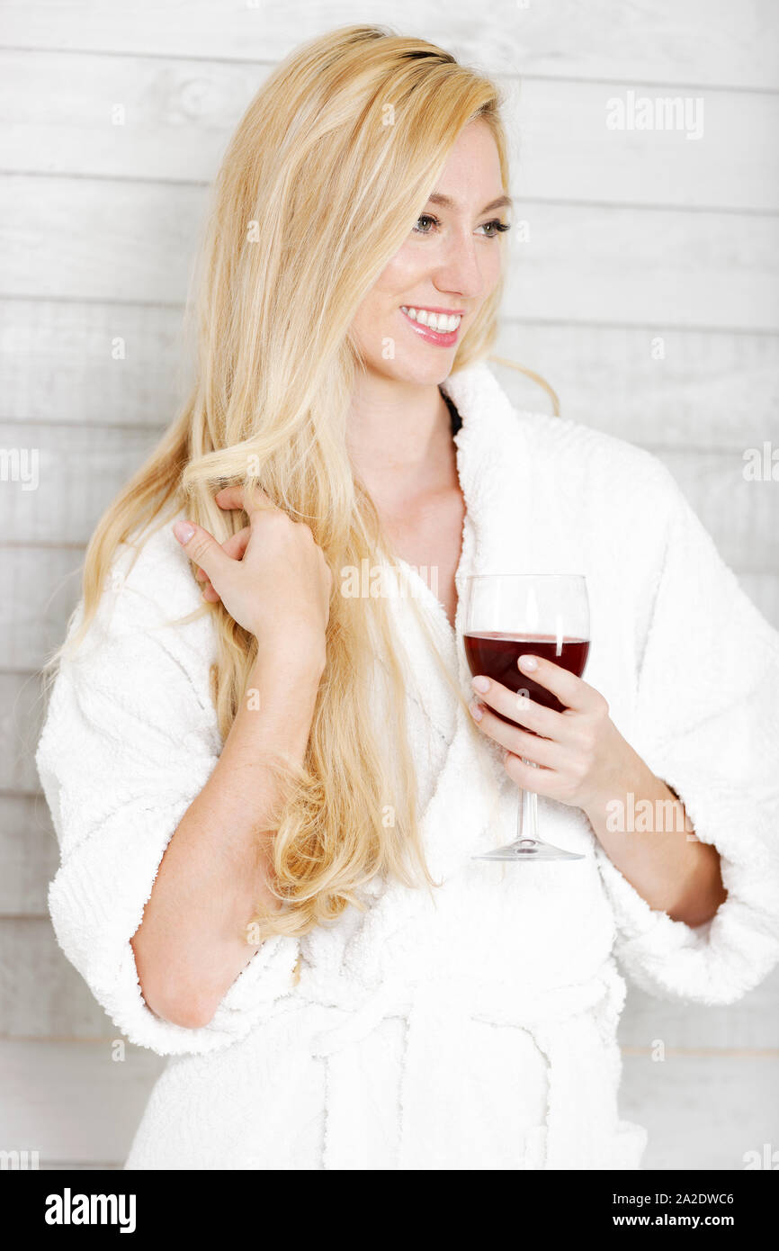 Schöne junge Frau in einem weißen Gewand, ein Glas Rotwein Stockfoto
