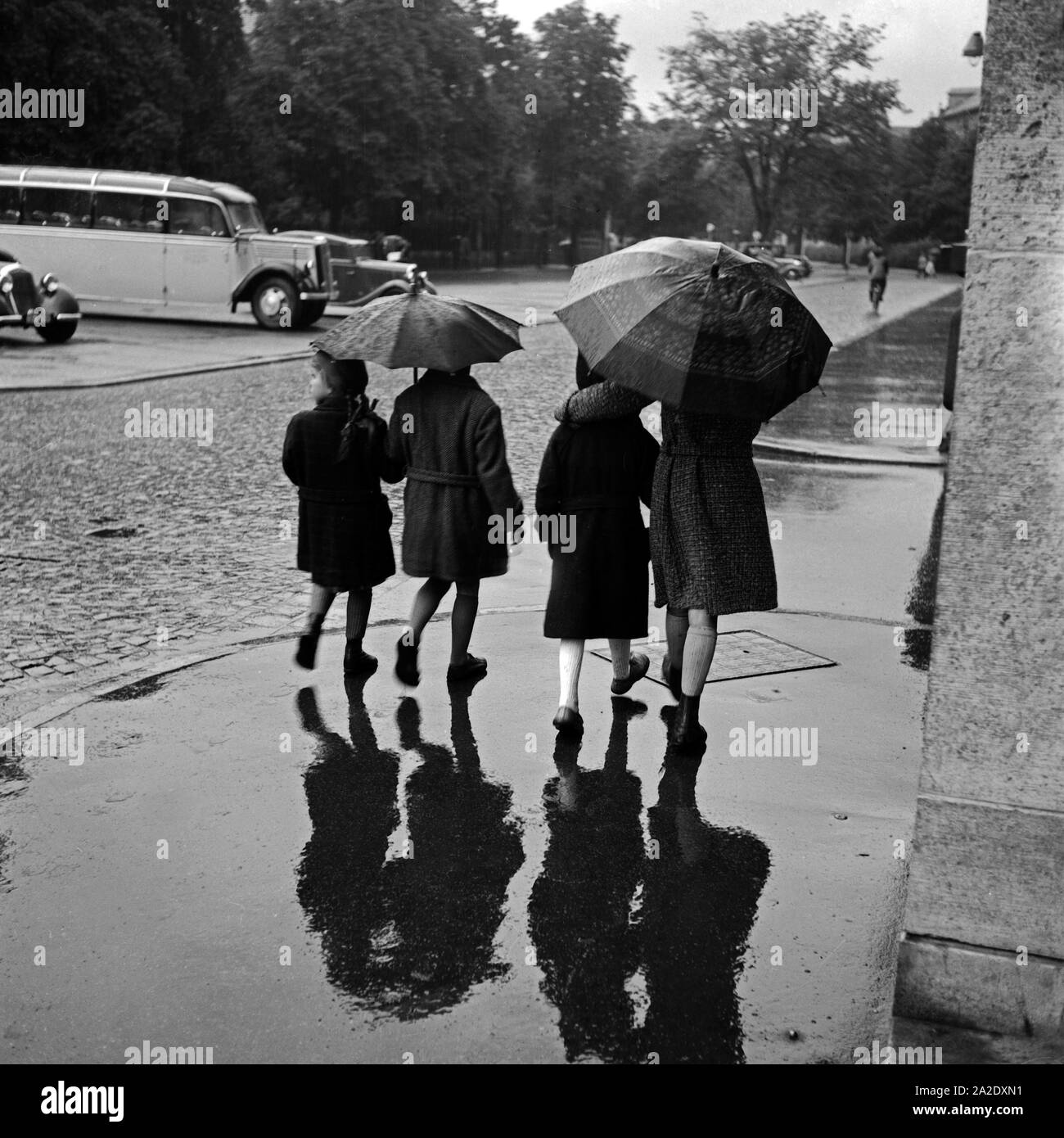 Vier Kinder im Regen unter dem Regenschirm, Deutschland 1930er Jahre. Vier Kinder im Regen unter ihren Schirmen, Deutschland 1930. Stockfoto