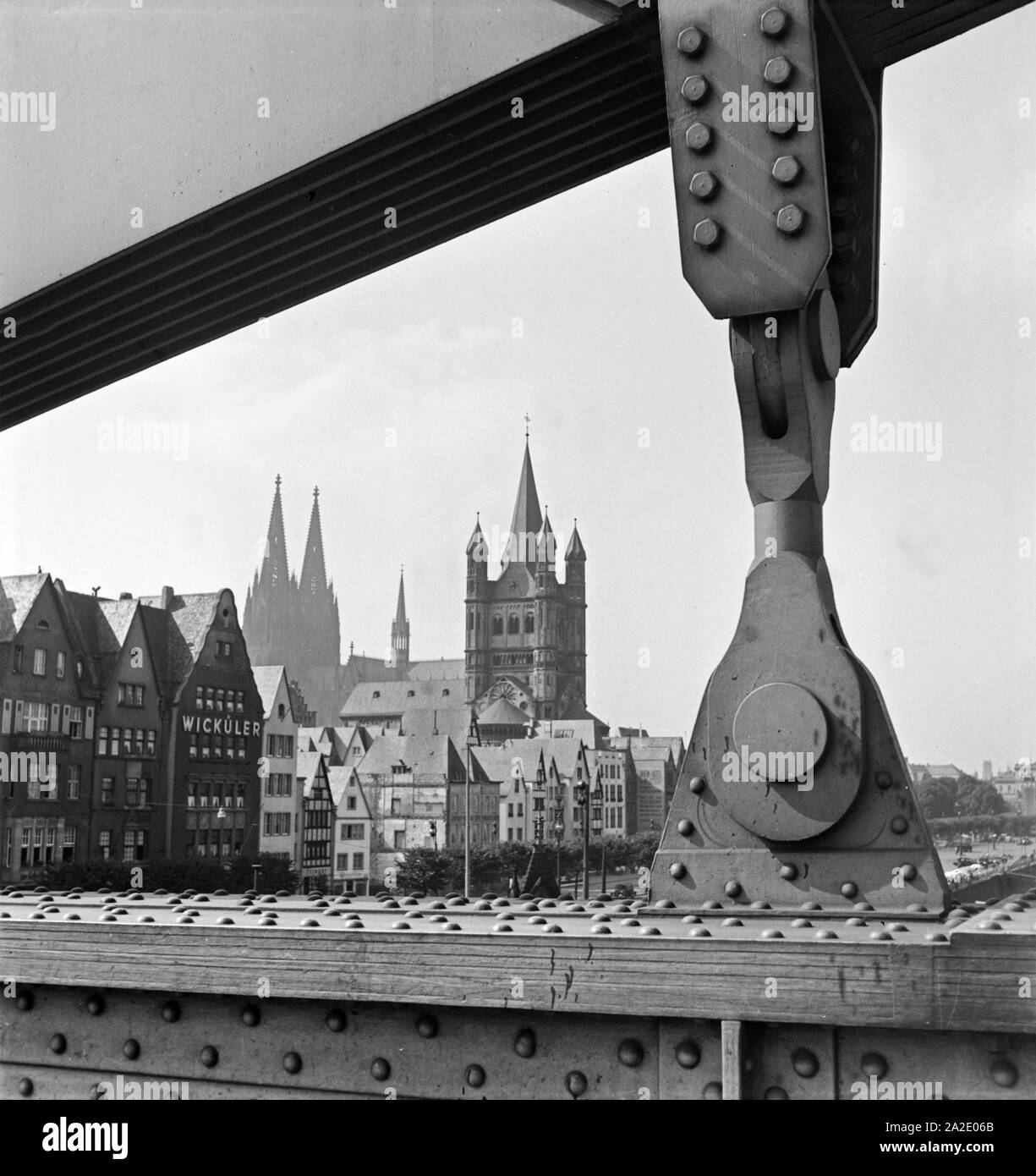 Altstadt von Köln mit Dom und Groß St. Martin Sterben, durch einen Aufhänger der Hindenburgbrücke gesehen, 1930er Jahre. Alte Stadt Köln mit Dom und St. Martin Kirche, die durch die Drähte der alte Hindenburg Brücke gesehen, 1930er Jahre. Stockfoto