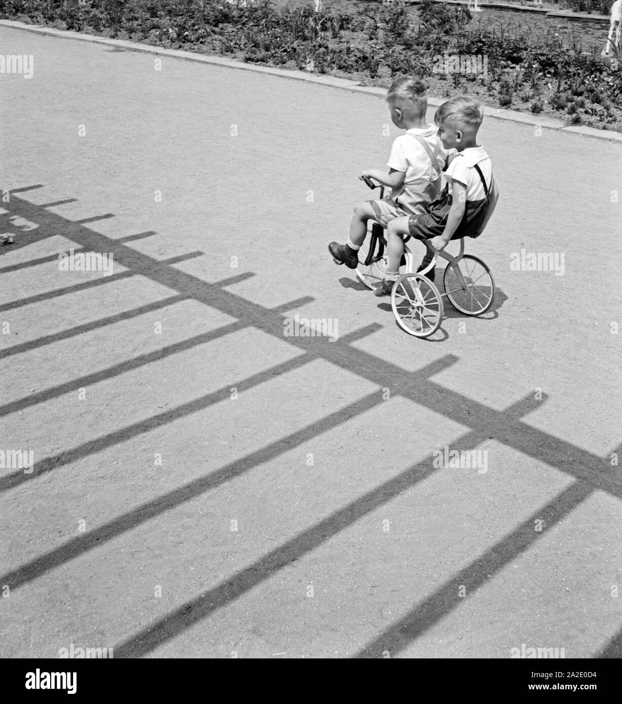 Zwei kleine Jungen fahren auf einem Dreirad in Chemnitz, Deutschland 1930er Jahre. Zwei kleine Jungen Reiter ein Dreirad in Chemnitz, Deutschland 1930. Stockfoto