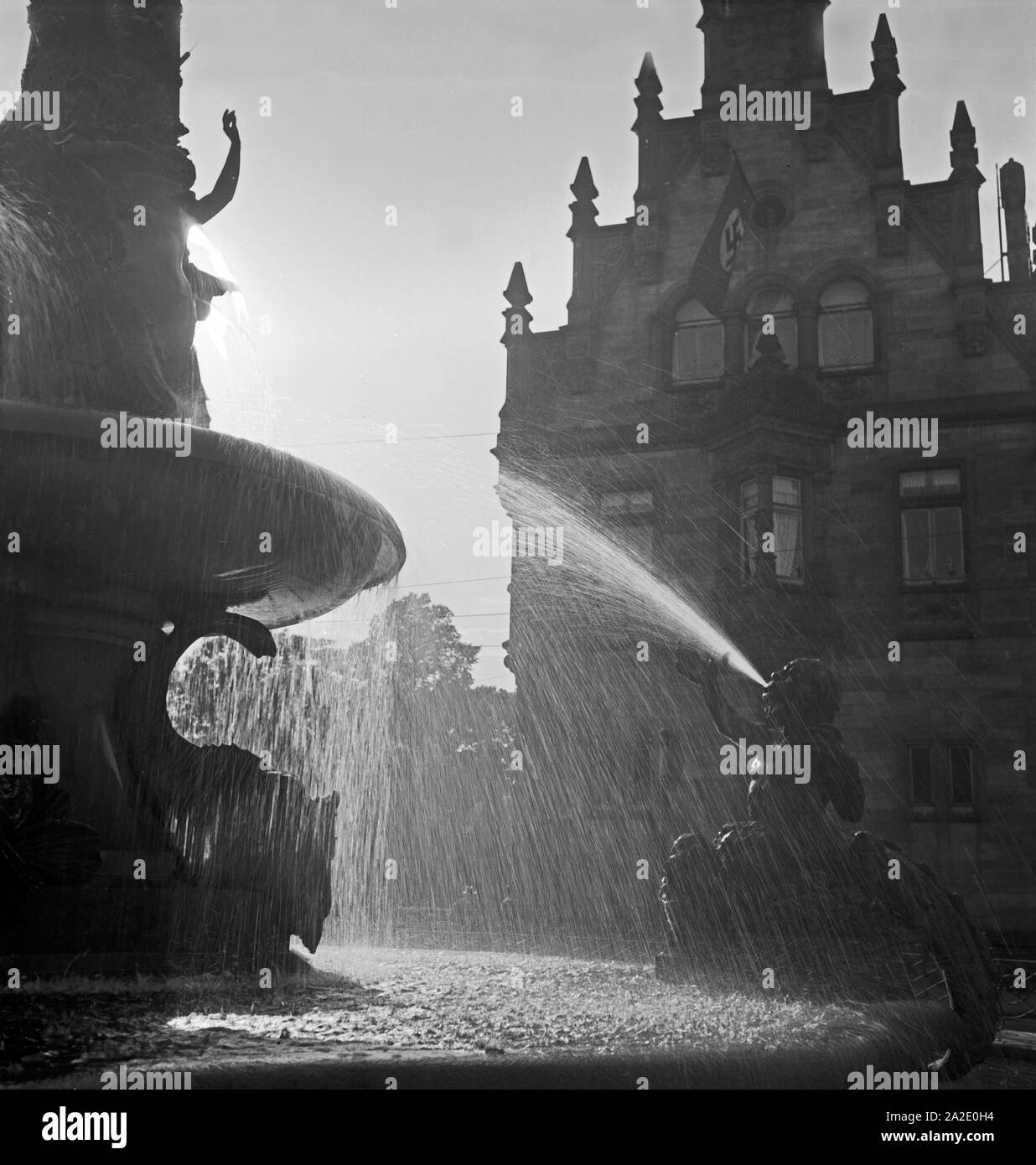 Springbrunnen im Gegenlicht vor einem stufengiebelhaus in Hannover, Deutschland 1930er Jahre. Im Gegenlicht vor einem Gebäude mit Stufengiebel in Hannover, Deutschland 1930 Fountian. Stockfoto