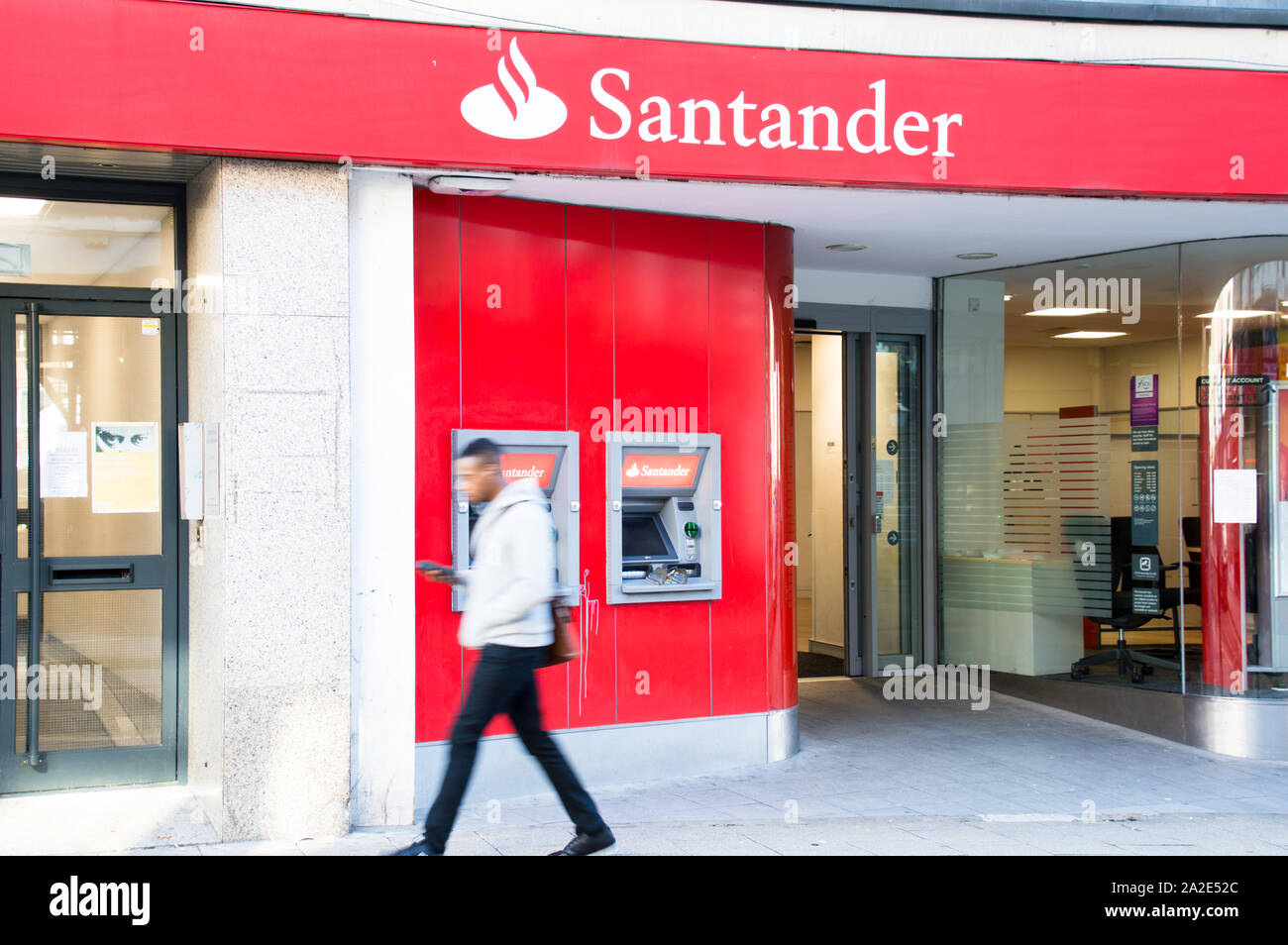 Ein Santander Bank Filiale an der High Street, wo eine Person an der ATM in eine verschwommene Bewegung Stockfoto