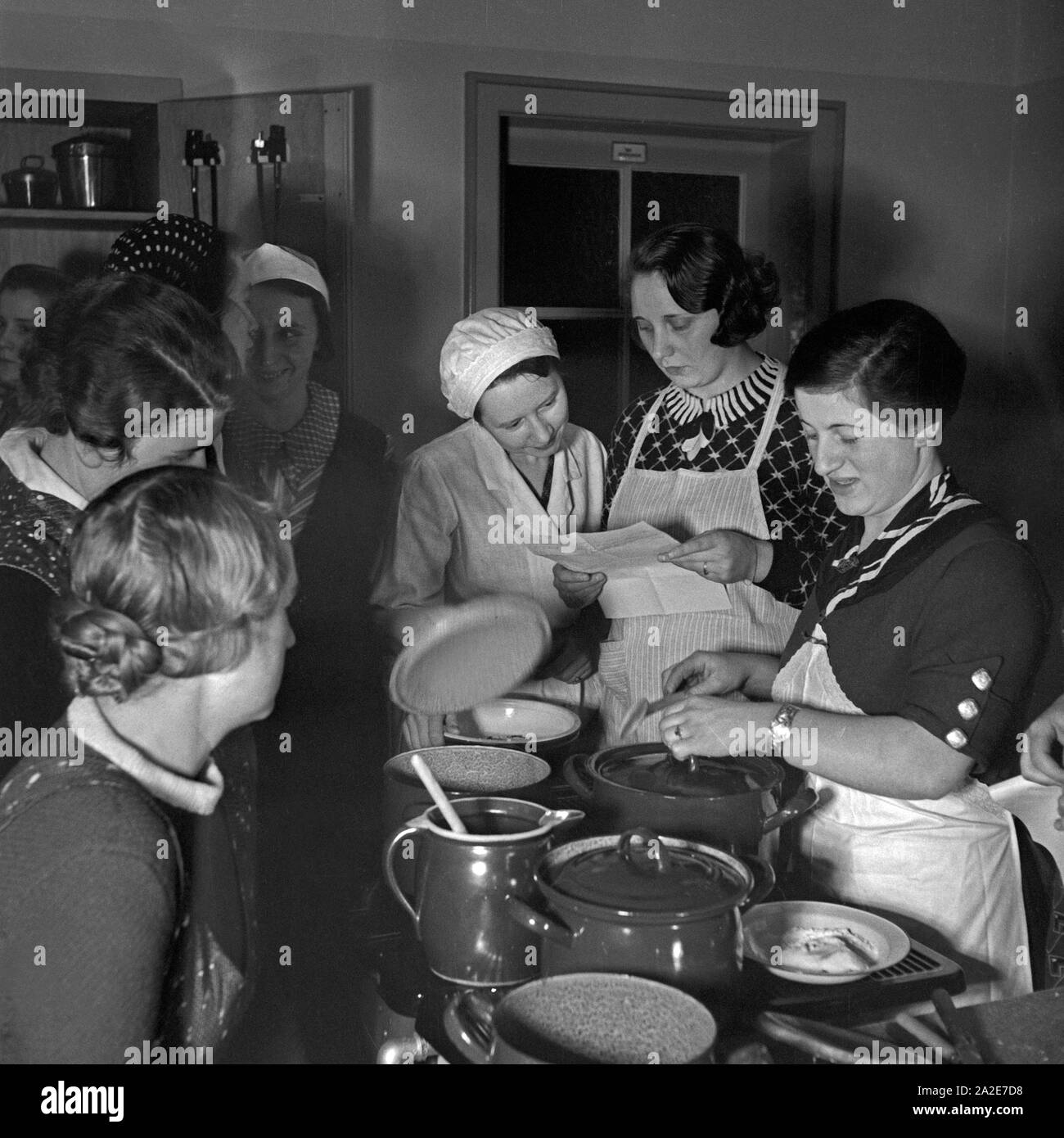 Frauen lernen Prävention und Gesundheitserziehung bei einer Mütterschulung des Reichsmütterdienstes in Essen teil, Deutschland 1930er Jahre. Frauen lernen, wie sie bei einer Mutter Ausbildung der Reichsmuetterdienst in Essen, Deutschland der 1930er Jahre zu kochen. Stockfoto