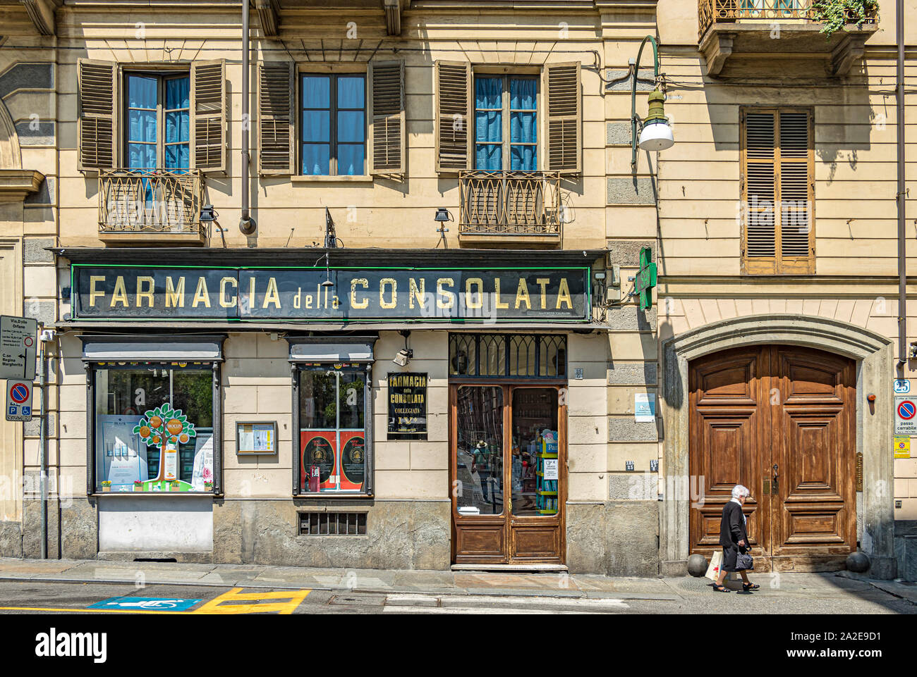 Eine ältere Frau hinter Farmacia della Consolata einer italienischen Apotheke auf der Via delle Orfane, Turin, Italien Stockfoto