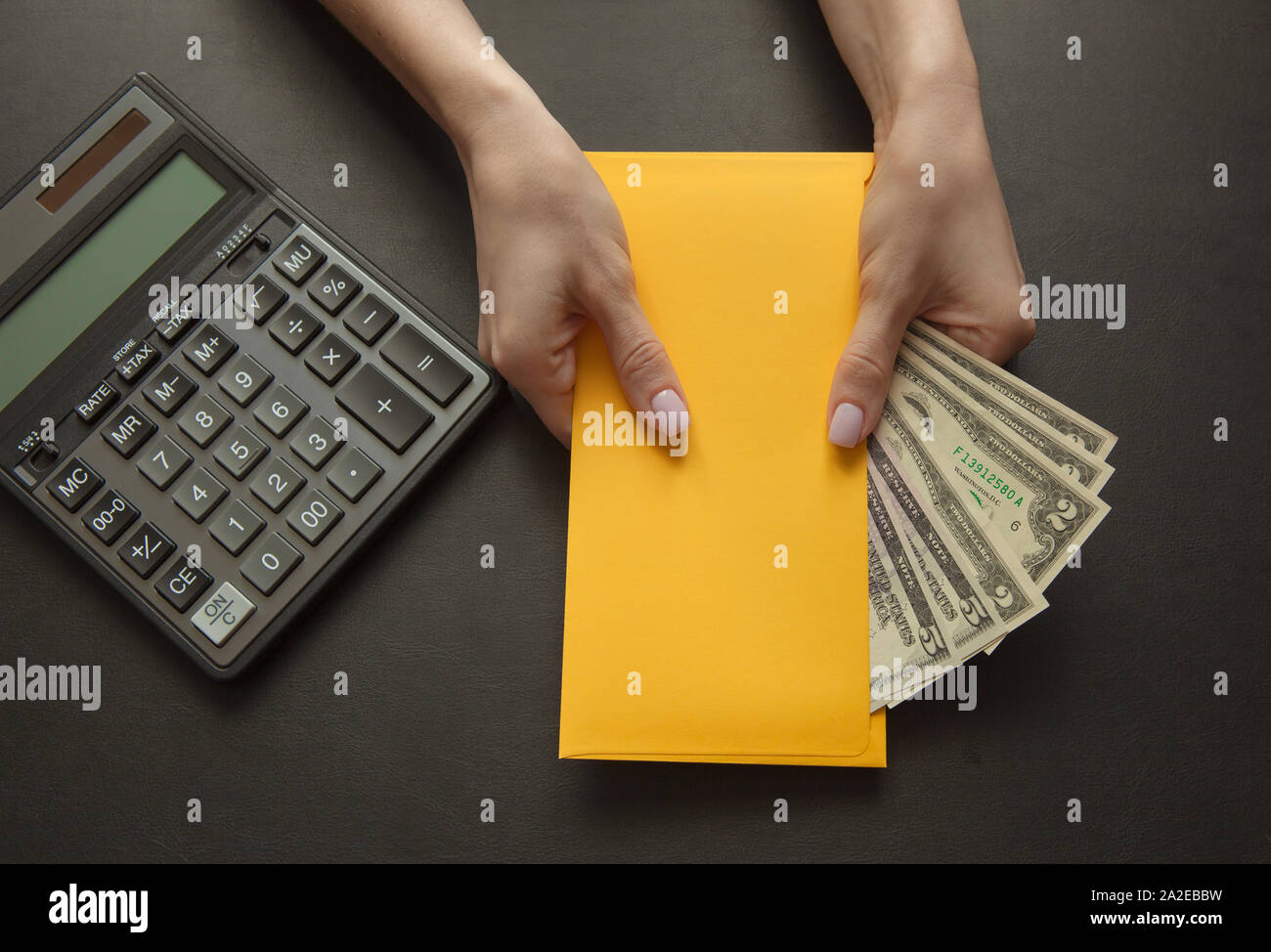 Konzept der Gehalt oder bestechungsgeld für die Arbeit. Gelber Umschlag mit Geld auf einem dunklen Tisch. Stockfoto