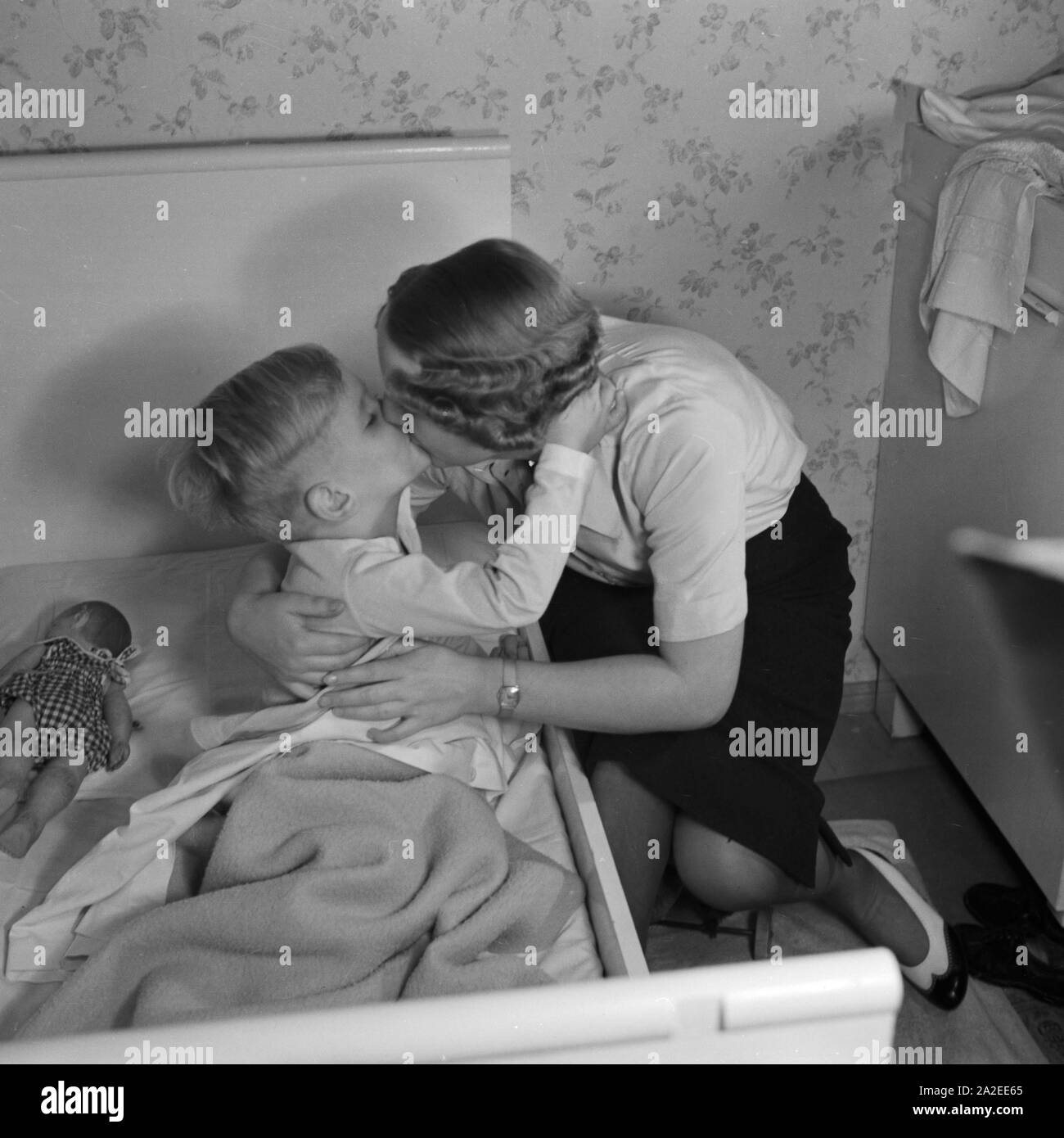 Eine Mutter unterstützt dabei, stand Sohn ins Bett und gibt ihm einen Gutenachtkuss, Deutschland 1930er Jahre. Eine Mutter ihren Sohn zu Bett und küsste ihm gute Nacht, Deutschland 1930. Stockfoto