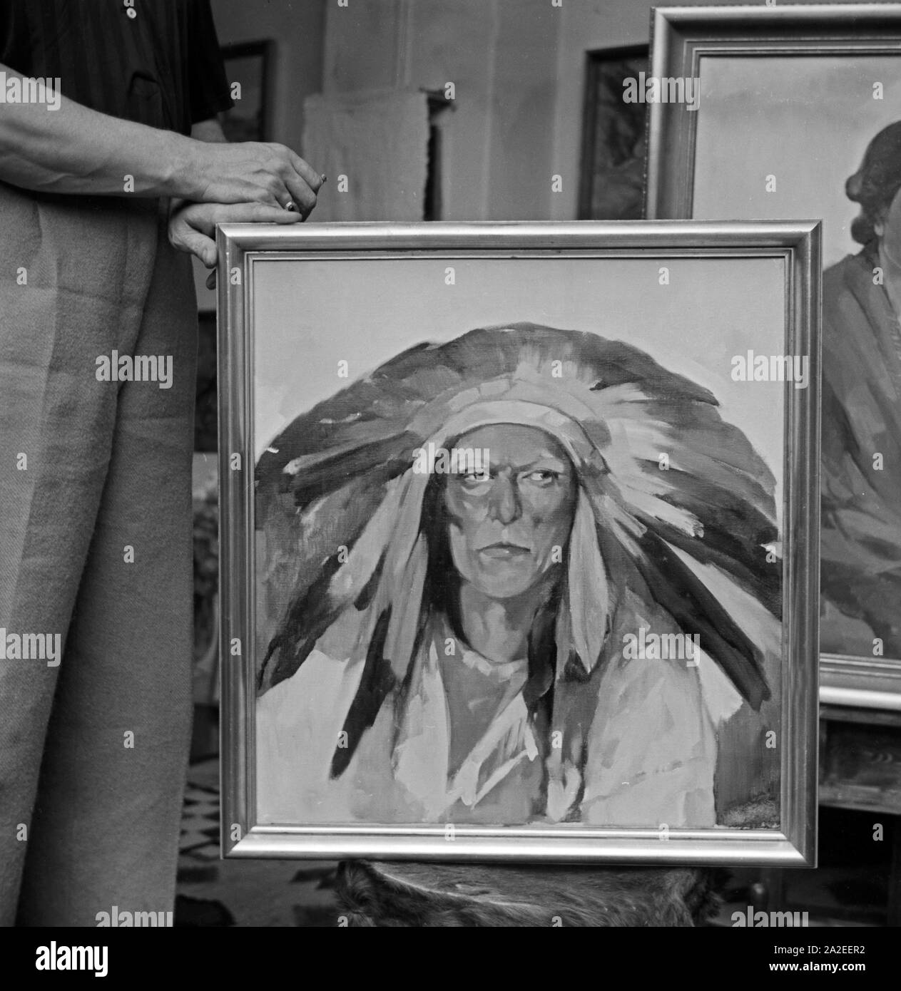 Ölgemälde mit dem Porträt eines Indianerhäuptlings Hans Paap und die Hände, die dieses Werk schufen, Deutschland, 1930er Jahre. Öl Gemälde mit einem Porträt von einem amerikanischen Einheimischen Stammesführer durch Maler Hans Paap und die Hände, die das Porträt, Deutschland 1930 s erstellt. Stockfoto