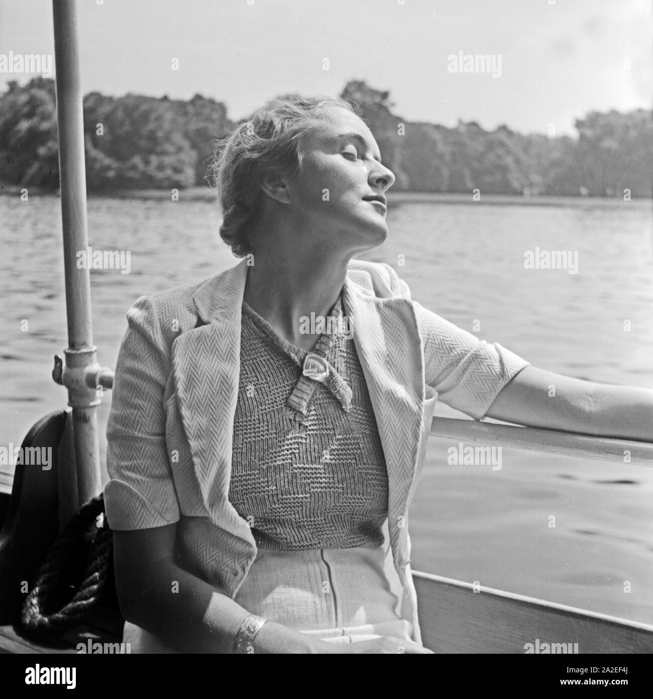 Eine junge Frau beim Sonnenbad in einem Auslugsdampfer auf der Spree in Berlin, Deutschland, 1930er Jahre. Eine junge Frau, ein Sonnenbad auf einem Boot am Spreeufer in Berlin, Deutschland 1930. Stockfoto