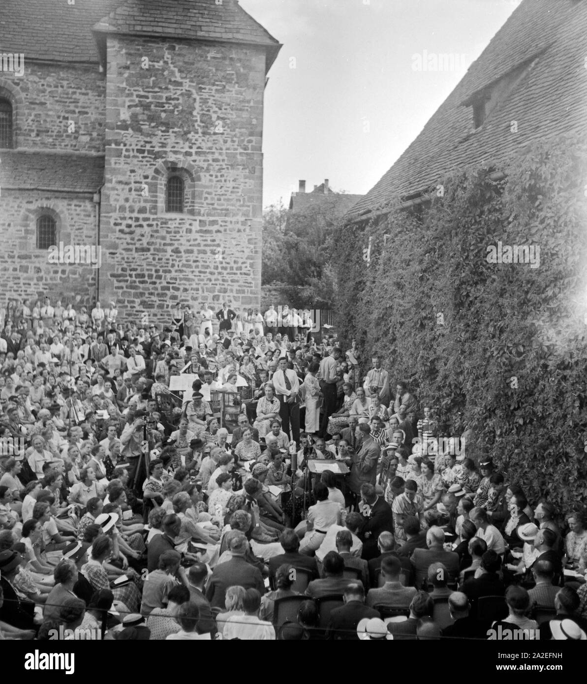 Der Schriftsteller Hans Grimm (am Schreibtisch) wird beim Dichtertreffen im Klosterhof von lippoldsberg an der Weser von Zuhörern umalgert, 1930er Jahre. Der deutsche Autor Hans Grimm (Schreibtisch) wird durch das Publikum an der Dichter treffen in Lippoldsberg, Hessen, 1930er Jahre umgeben. Stockfoto