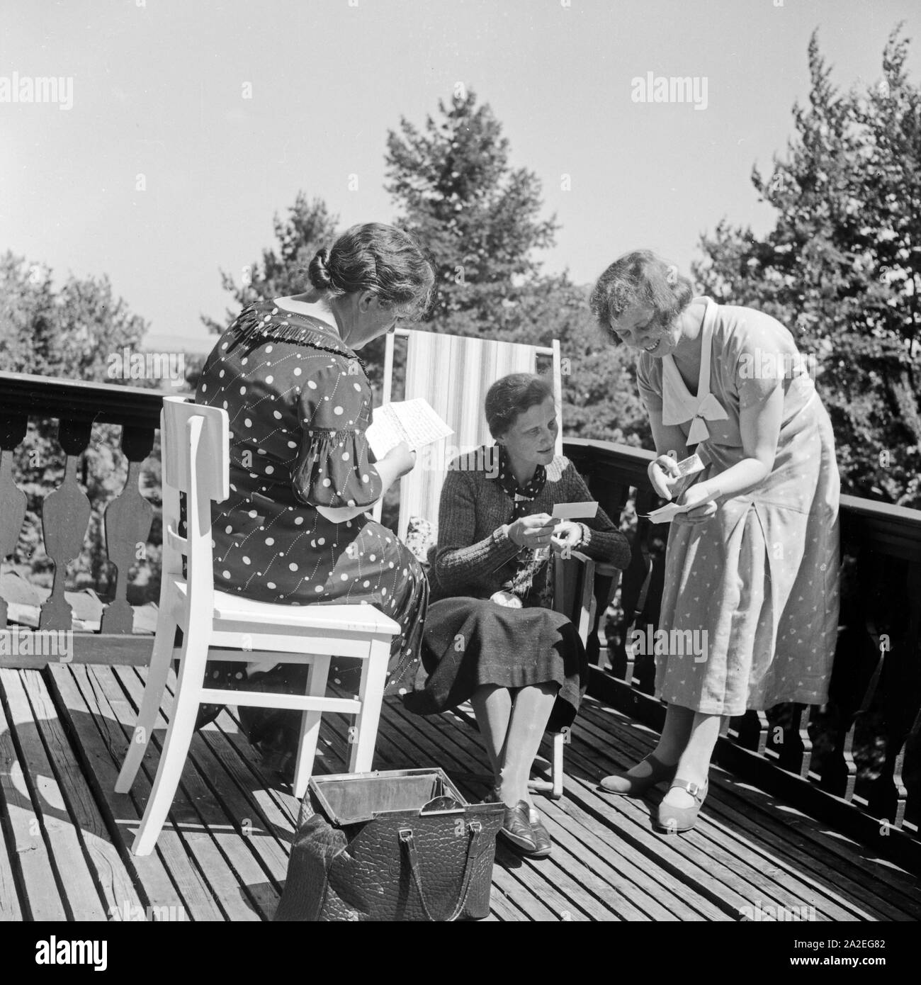Drei Frauen entspannen sich bei Handarbeit und einer Unterhaltung im Murmeln und Art Heim in Tabarz, Thüringer Wald, 1930er Jahre. Drei Frauen entspannen, während Sie einige fancywork und eine auf einen Balkon von einer Mutter und Kind Freizeit Home in Tabarz, Thüringen chat. Stockfoto