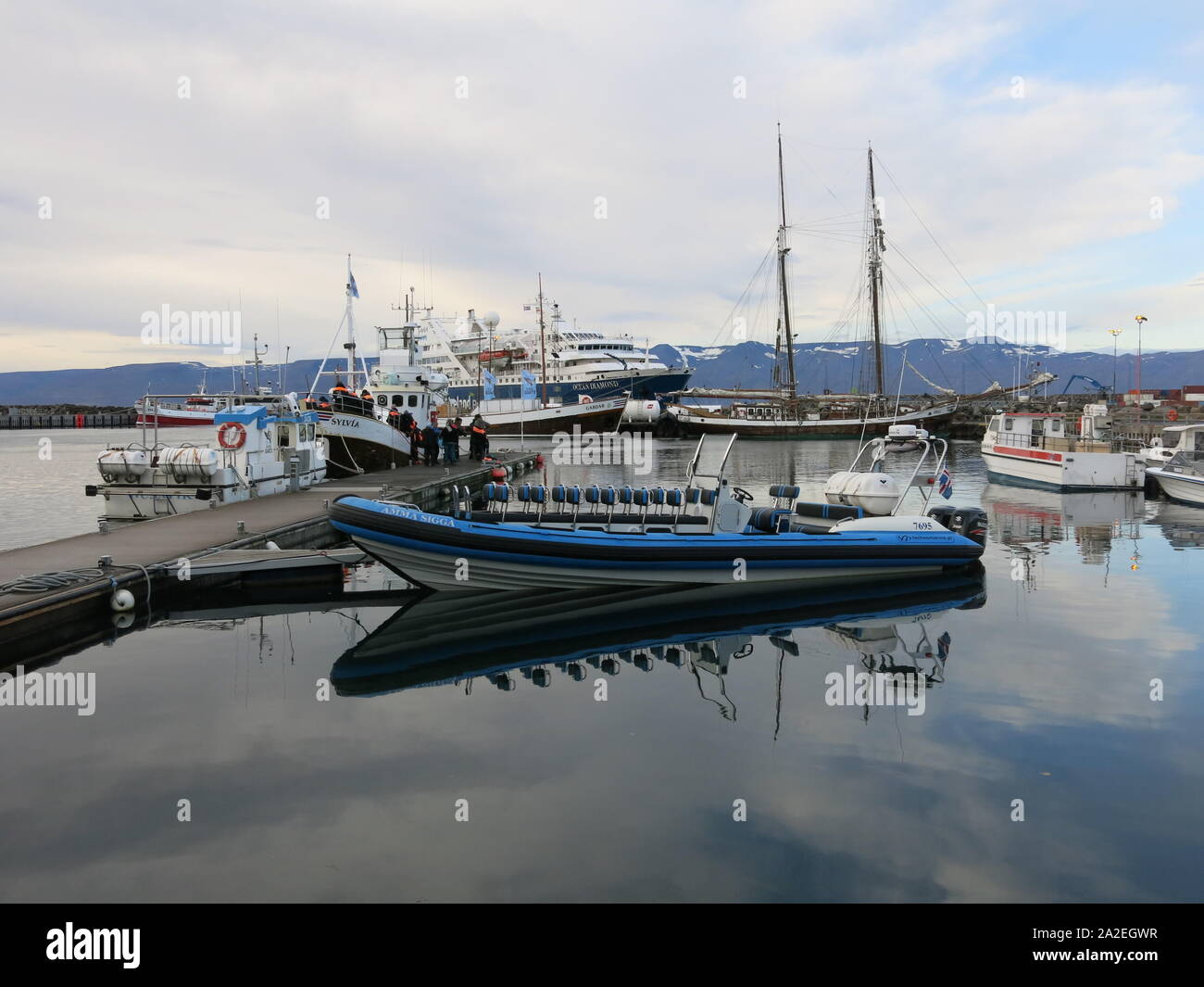 Blick auf den Hafen in Husavik, Walbeobachtung Islands Hauptstadt, mit einer Rippe, starr - geschält aufblasbares Boot am Steg vertäut. Stockfoto