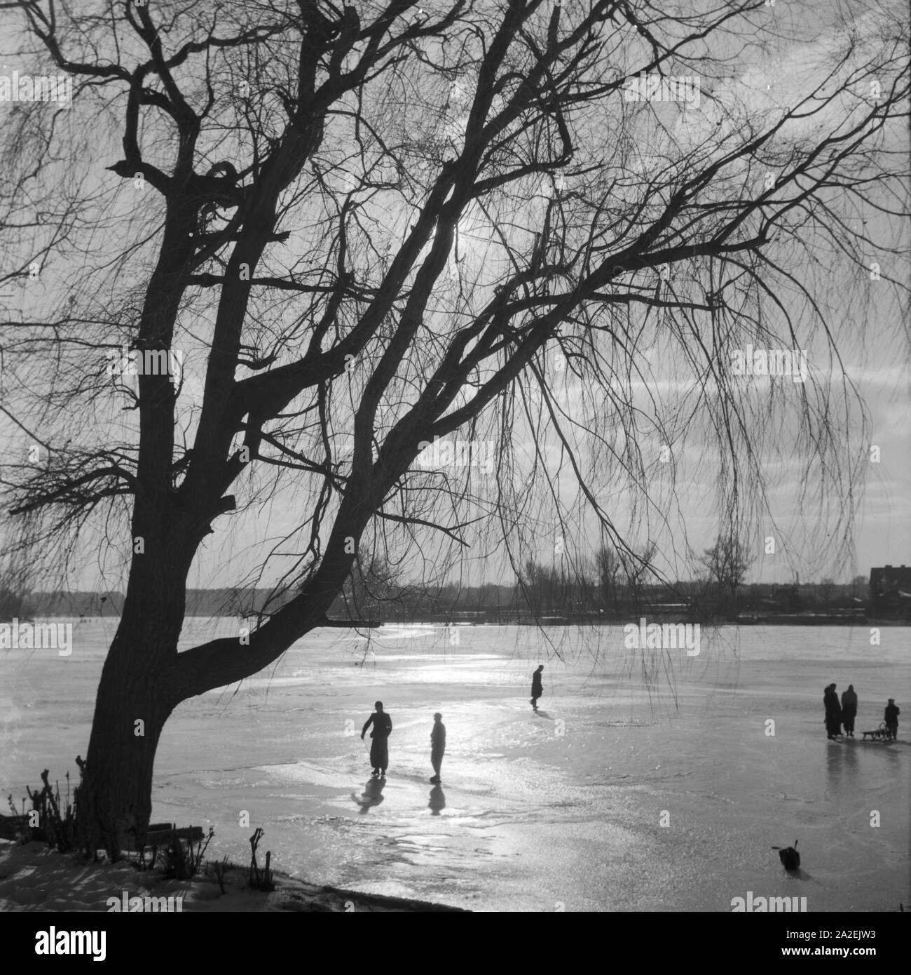 Menschen fahren Schlittschuh in einem zugefrorenen Sehen, Deutschland 1930er Jahre. Leute Eislaufen auf einem zugefrorenen See, Deutschland 1930. Stockfoto