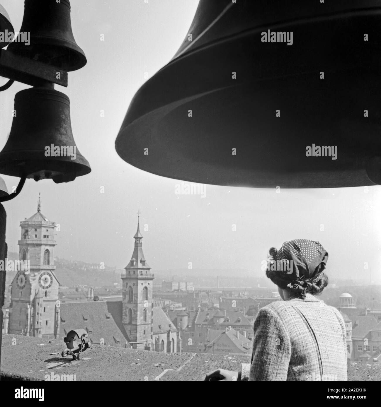 Eine Frau steht unter dem Geläut des Rathausturmes in Stuttgart und schaut hinüber zur Stiftskirche, Deutschland 1930er Jahre. Eine Frau unter den glockenschlag von Stuttgart City Hall anzeigen Stiftskirche, Deutschland 1930. Stockfoto