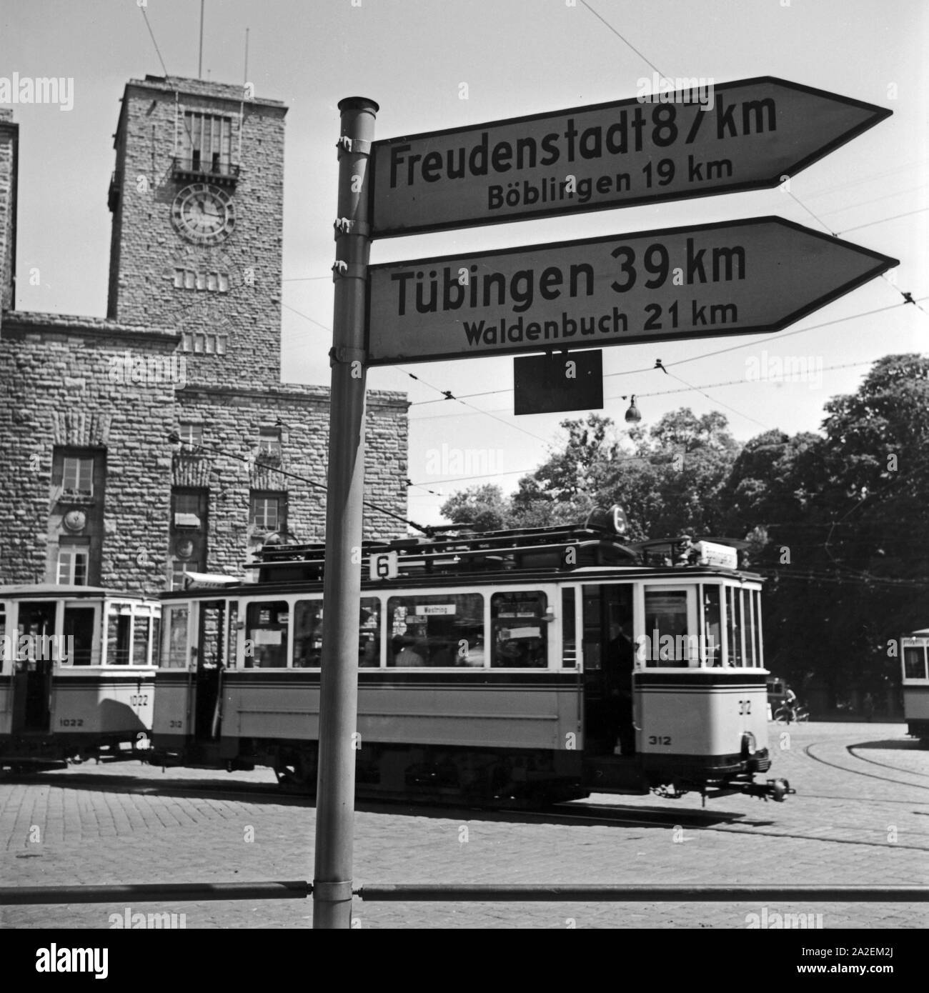 Wegweiser / Freudenstadt, Böblingen, Tübingen und Waldenbuch vor einer Straßenbahn der Linie 6 am Hauptbahnhof Stuttgart, Deutschland 1930er Jahre. Wegweiser zu Freudenstadt, Böblingen, Tübingen und Waldenbuch vor einer Straßenbahn der Linie Nr. 6 am Hauptbahnhof Stuttgart, Deutschland 1930. Stockfoto