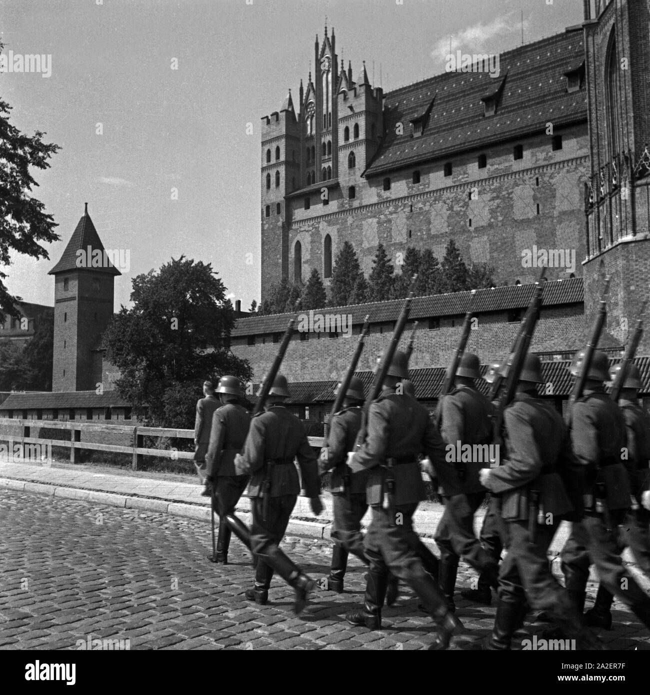 Eine Trupp Soldaten zieht an der Marienburg in Ostpreußen vorbei, Deutschland 1930er Jahre. Eine Gruppe von Soldaten marschieren durch die ordensburg Marienburg, Ostpreußen, Deutschland 1930. Stockfoto