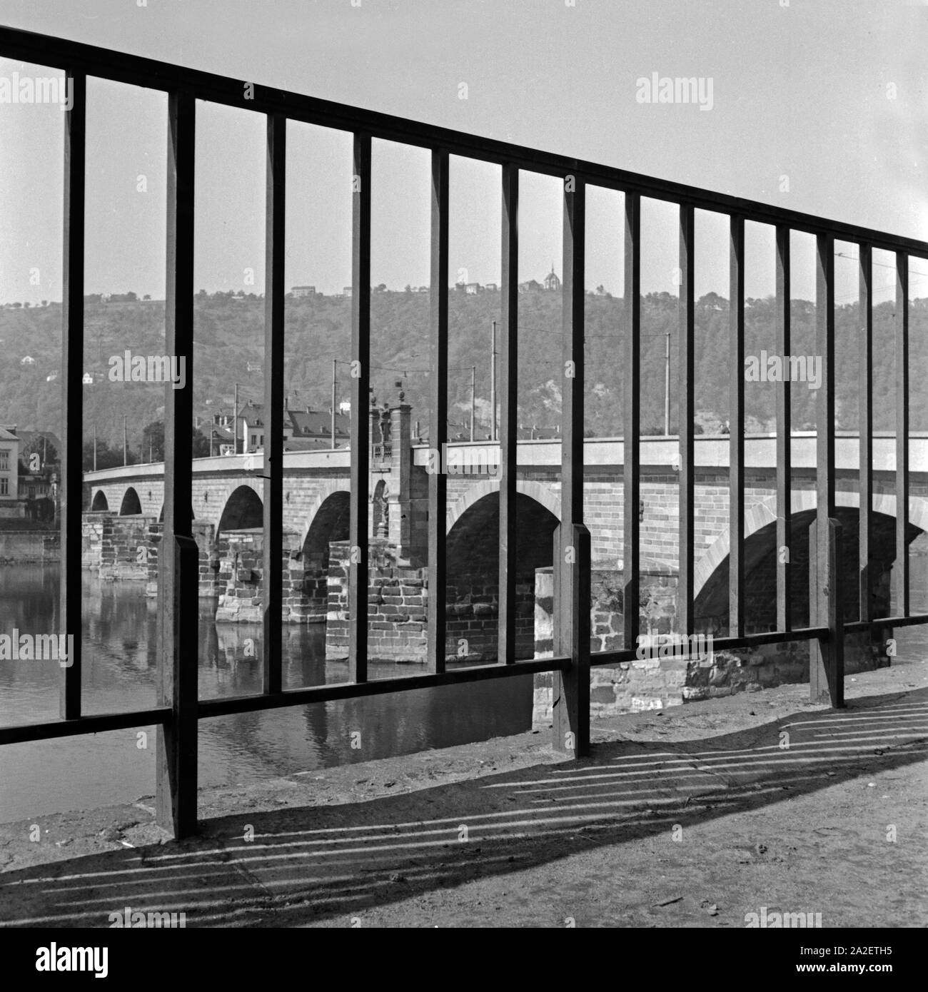 Die Trierer Alte Moselbrücke, durch ein Gitter am Ufer der Mosel gesehen, Deutschland 1930er Jahre. Die alte Brücke über die Mosel in Trier, durch ein Geländer am Ufer gesehen, Deutschland 1930. Stockfoto