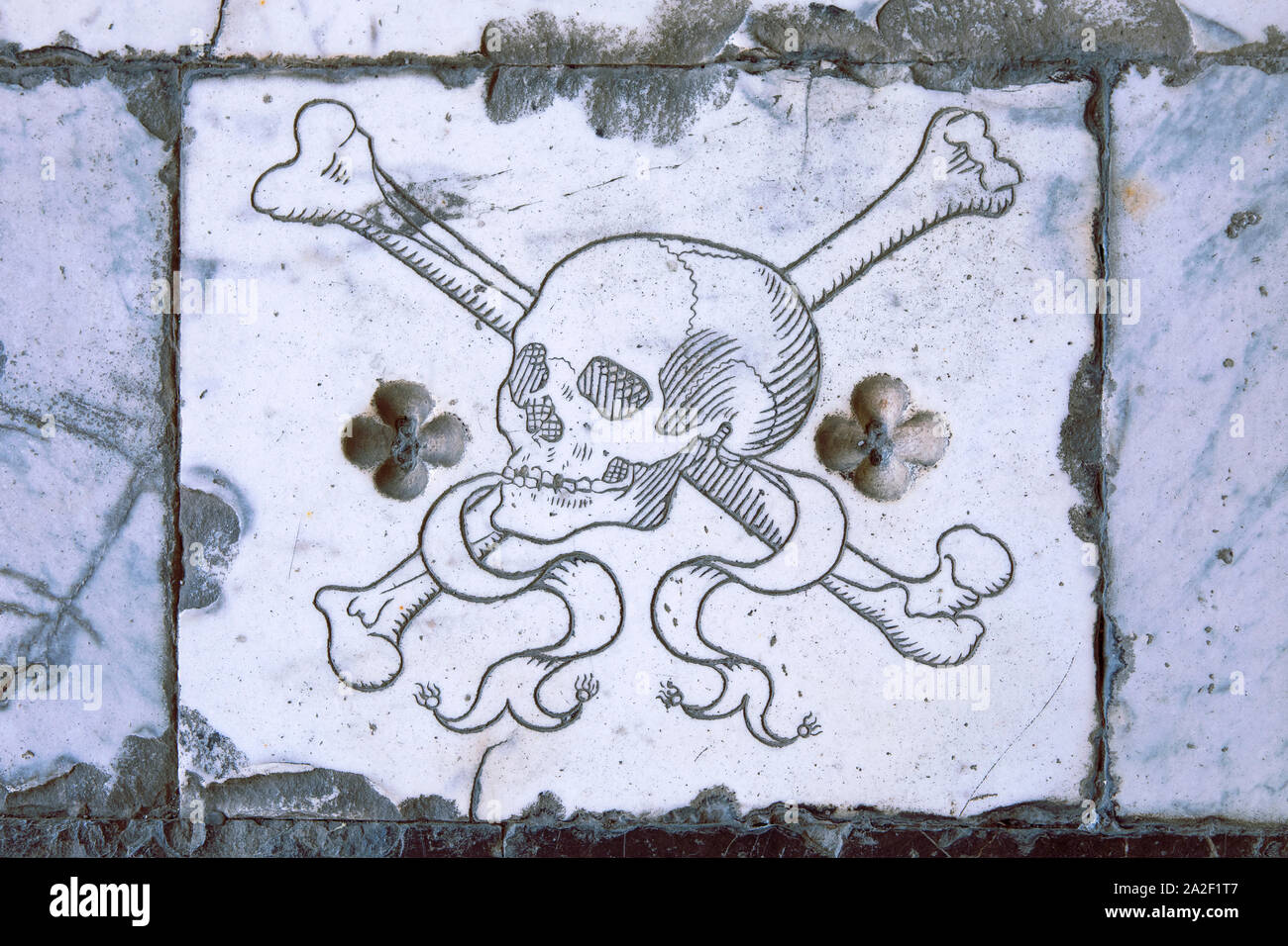 Klassische Totenkopf mit gekreuzten Knochen Symbol in Marmor Stein auf italienischen Grab. Mittelalterliche Krypta. Antike Schädel Muster, Memento mori. Stockfoto