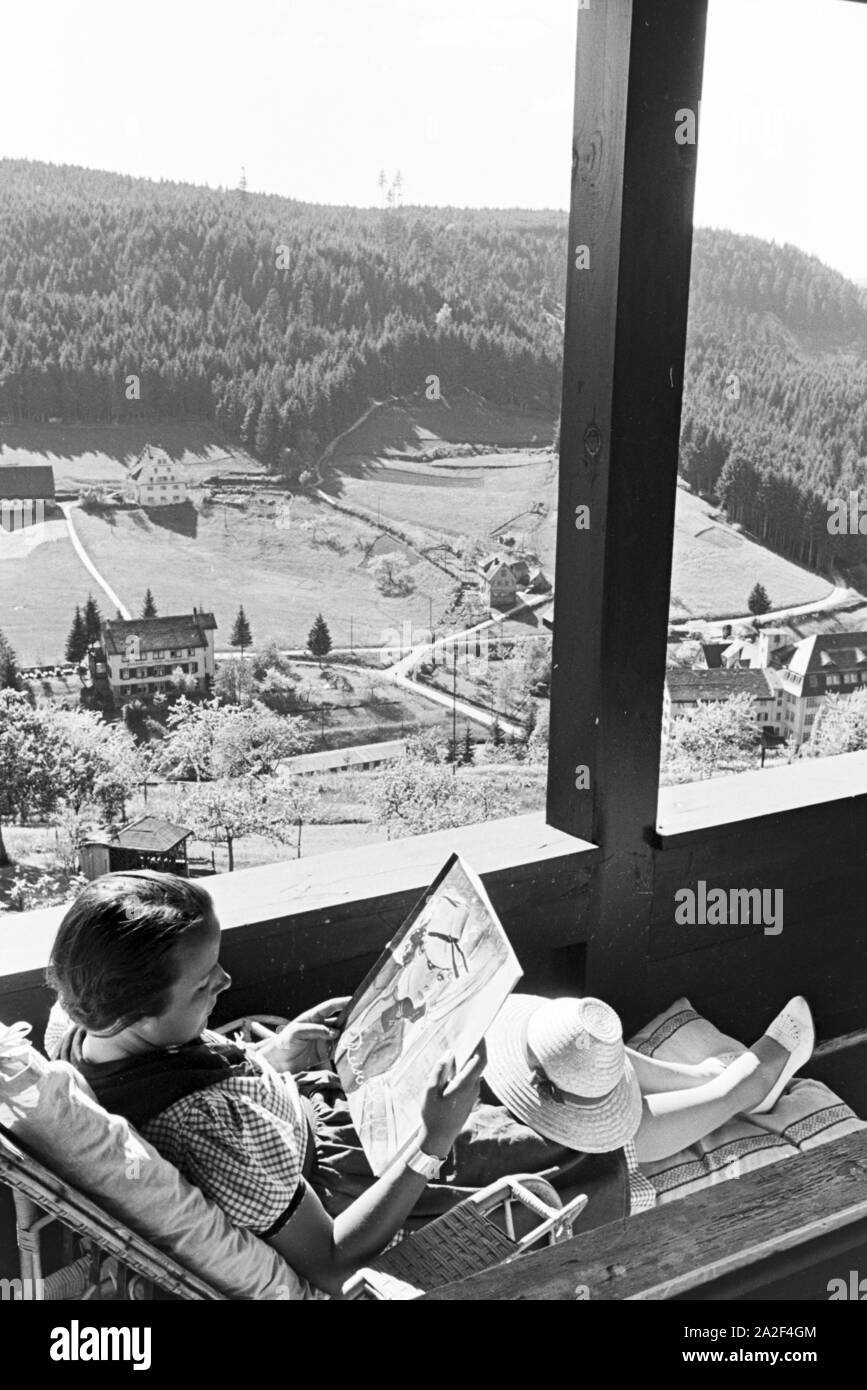 Eine junge Frau entspannt bei der Zeitschriftenlektüre auf dem Balkon, Freudenstadt, Deutschland 1930er Jahre. Eine junge Frau bei einem Magazin auf dem Balkon, Freudenstadt, Deutschland 1930. Stockfoto