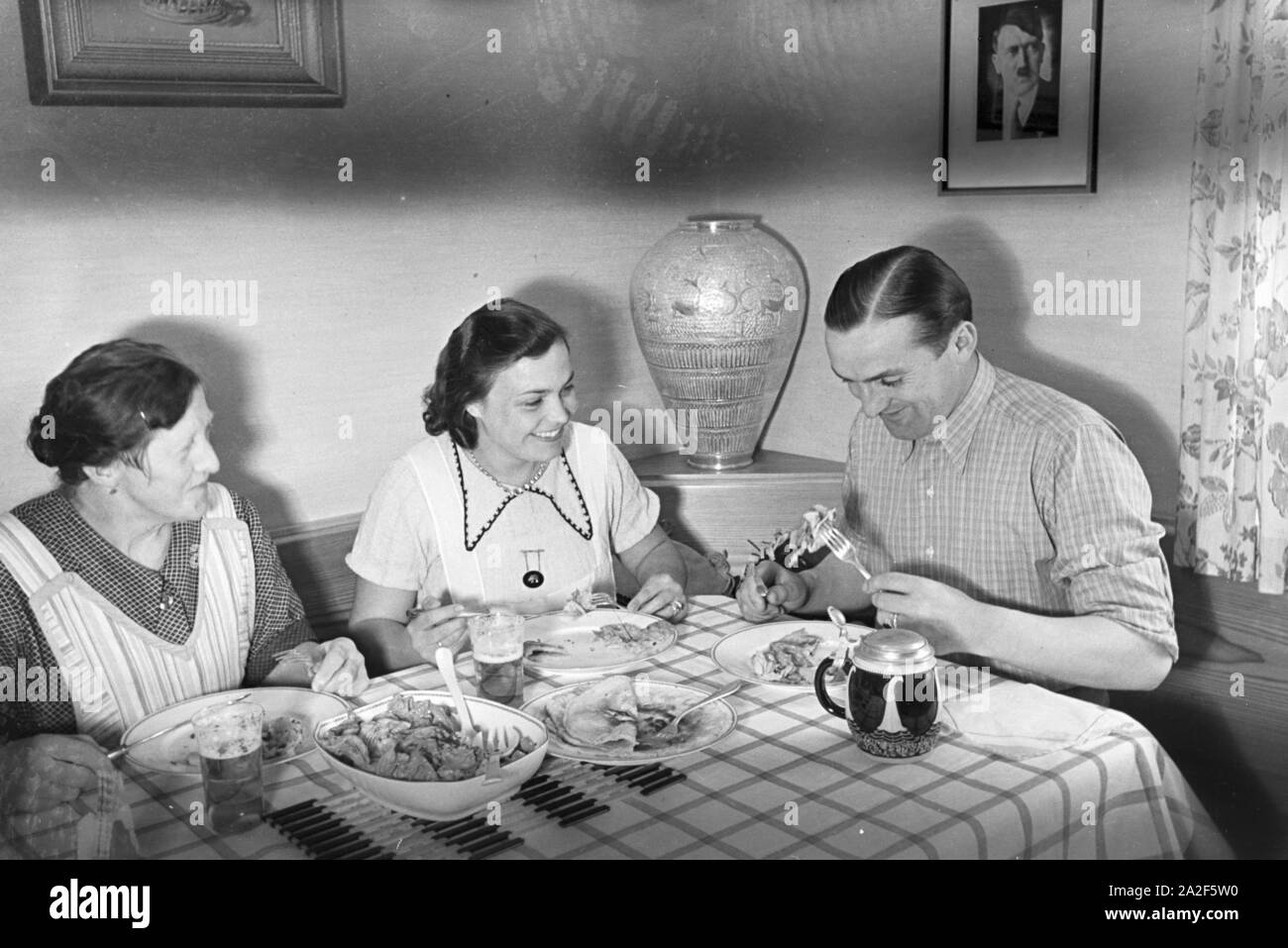 Der autorennfahrer Hermann Lang beim Essen mit seiner Familie, Deutschland 1930er Jahre. Der Rennfahrer Hermann Lang ein Mittagessen mit seiner Familie, Deutschland 1930. Stockfoto