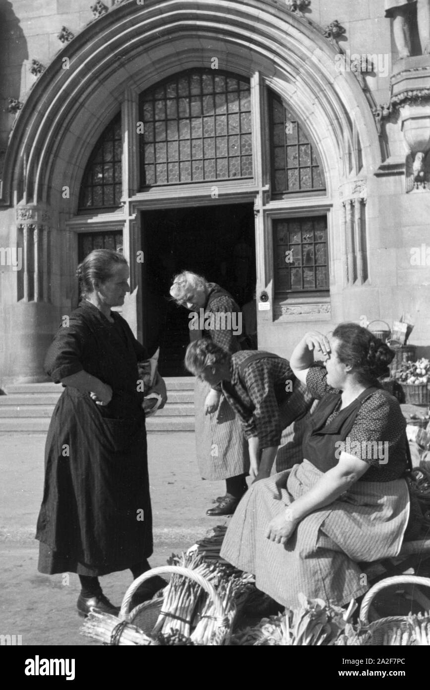 Verkäuferinnen bei einem Gespräch mit dem Wochenmarkt auf dem Stuttgarter Marktplatz, Deutschland 1930er Jahre. Marketingspezialisten in einem Chat auf dem Wochenmarkt auf dem Marktplatz in Stuttgart, Deutschland 1930. Stockfoto