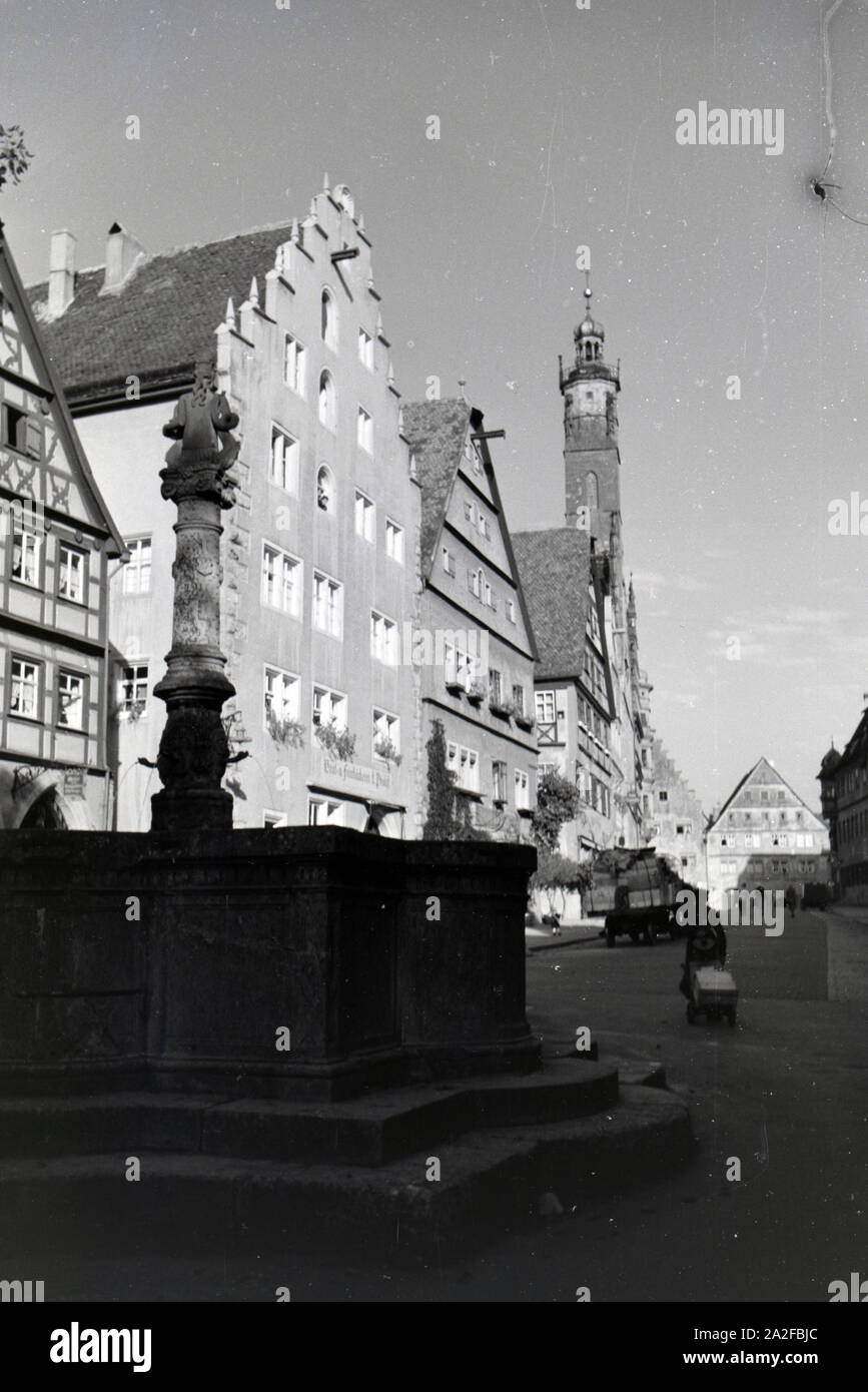 Ein Springbrunnen mit des imposanten Rathauses in Rothenburg o.d. Tauber, von dem der gotische Teil mitsamt hohem Turm im Hintergrund sichtbar ist, Deutschland 1930er Jahre. Ein Brunnen in der Nähe der beeindruckenden Rathaus in Rothenburg o.d. Tauber, mit der gotische Teil und die hohe towerin den Hintergrund, Deutschland 1930. Stockfoto