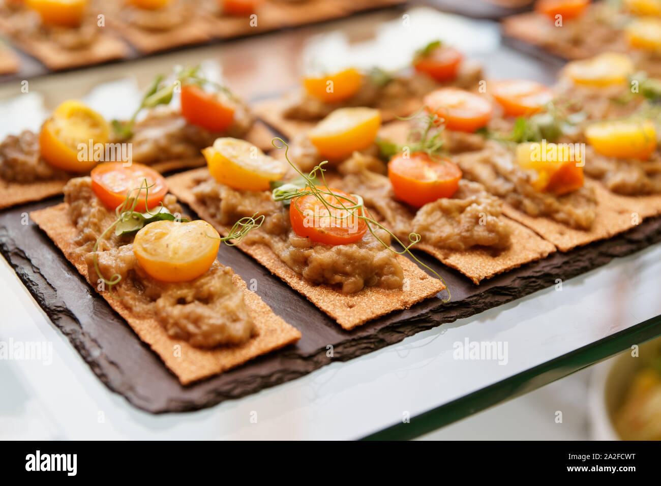 Knusprige Brote mit Aubergine bran Mash und Kirschtomaten auf Tisch im Restaurant Stockfoto