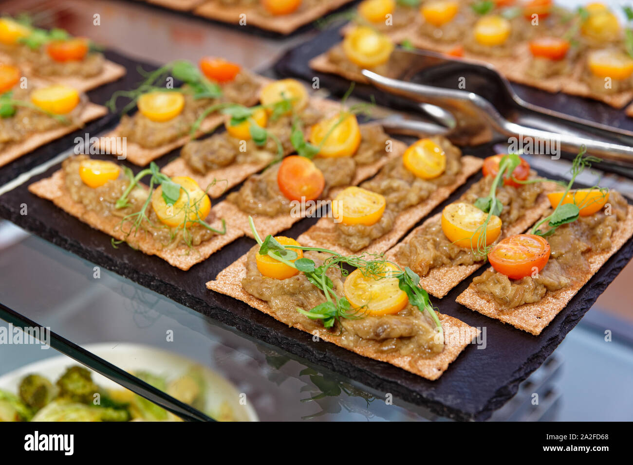 Knusprige Brote mit Aubergine bran Mash und Kirschtomaten auf Catering Tabelle Stockfoto