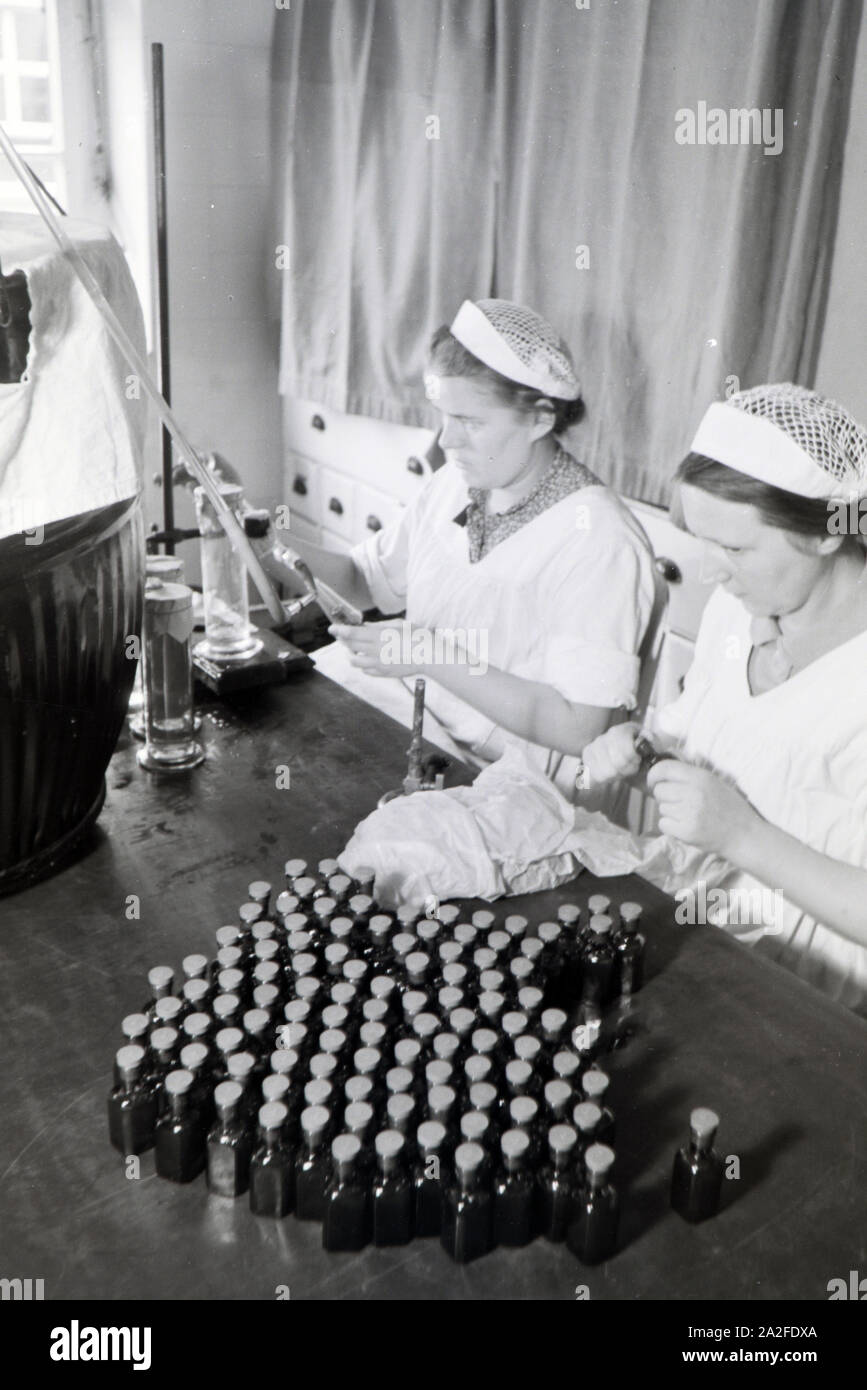 Zwei Laborantinnen füllen in Arbeit der Behringwerke Medikamente in kleine Flaschen ab, Marburg, Deutschland 1930er Jahre. Zwei lab Assistenten sind Befüllen Medikation in kleinen Flaschen im Labor der Behringwerke, Marburg, Deutschland 1930. Stockfoto