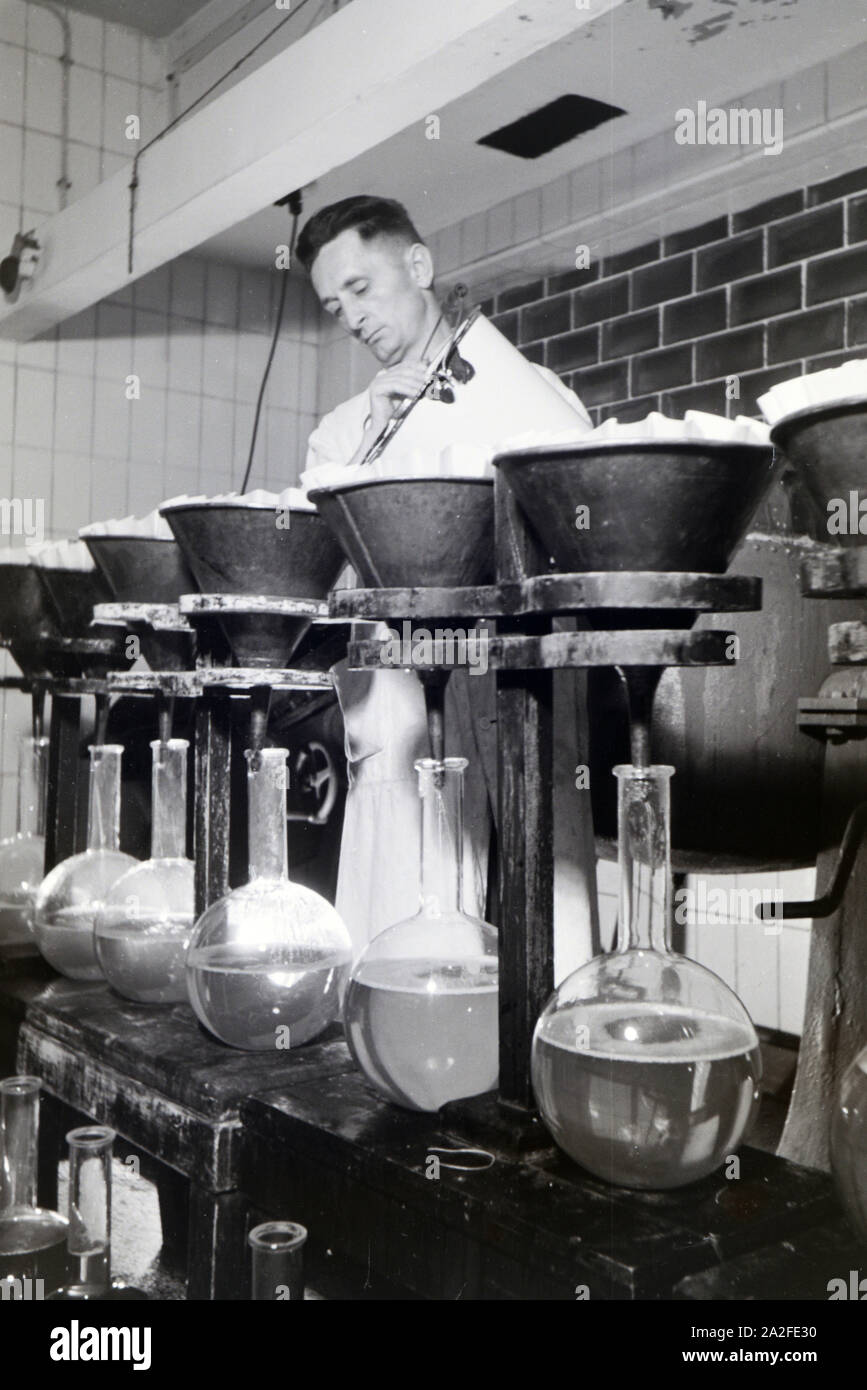 Ein Laborant füllt Medikamentenproben in große Glaskolben in Arbeit der Behringwerke ab, Marburg, Deutschland 1930er Jahre. Eine Lab Assistant füllt sich Medizin Proben in grossen Glaskolben in einem Labor der Behringwerke, Marburg, Deutschland 1930. Stockfoto
